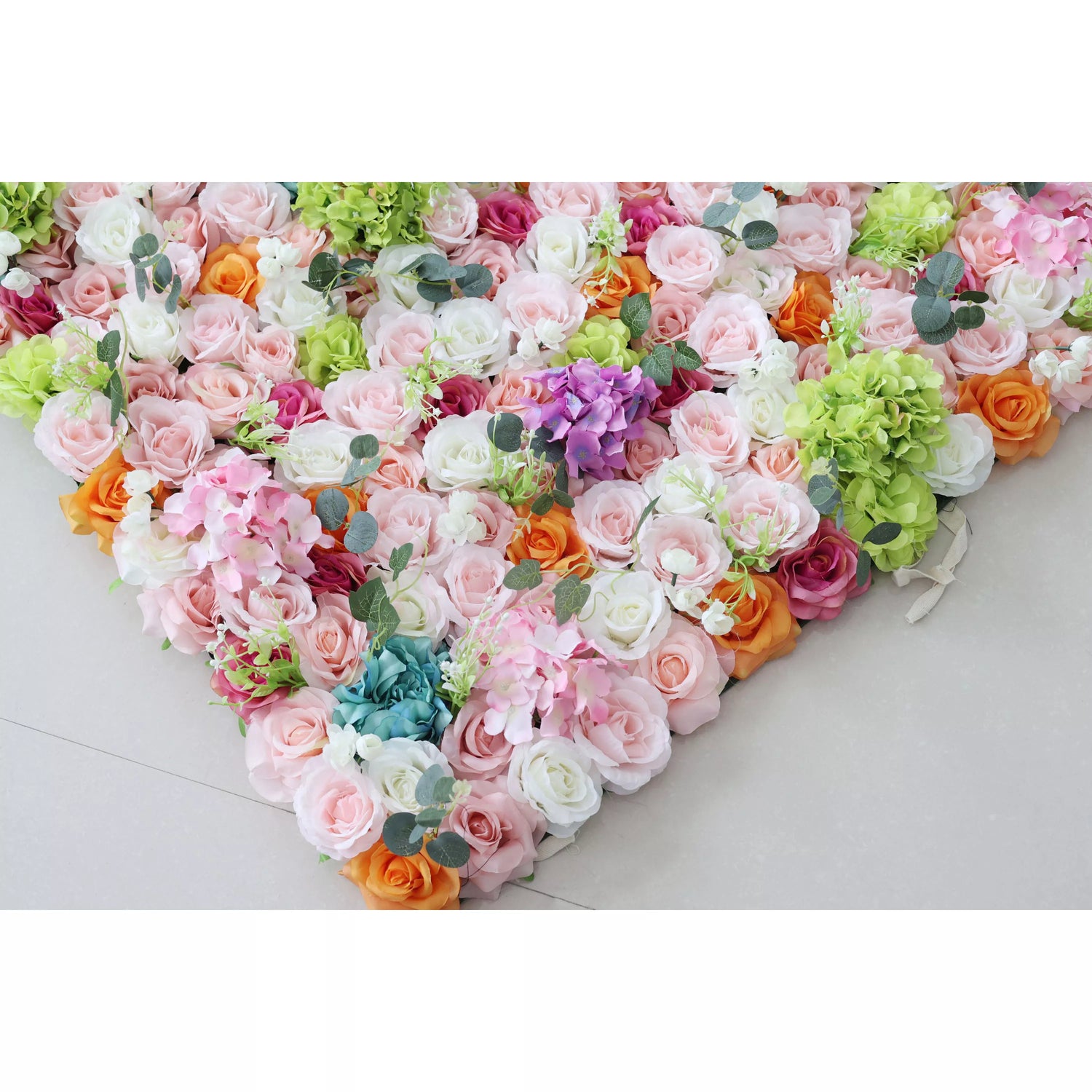 This is a heart - shaped artificial flower arrangement. It features a mix of roses in colors like pink, white, orange, purple, and blue, along with hydrangeas and eucalyptus - like leaves. Ideal for decorative purposes at events such as weddings or celebrations, creating a romantic and colorful ambiance.