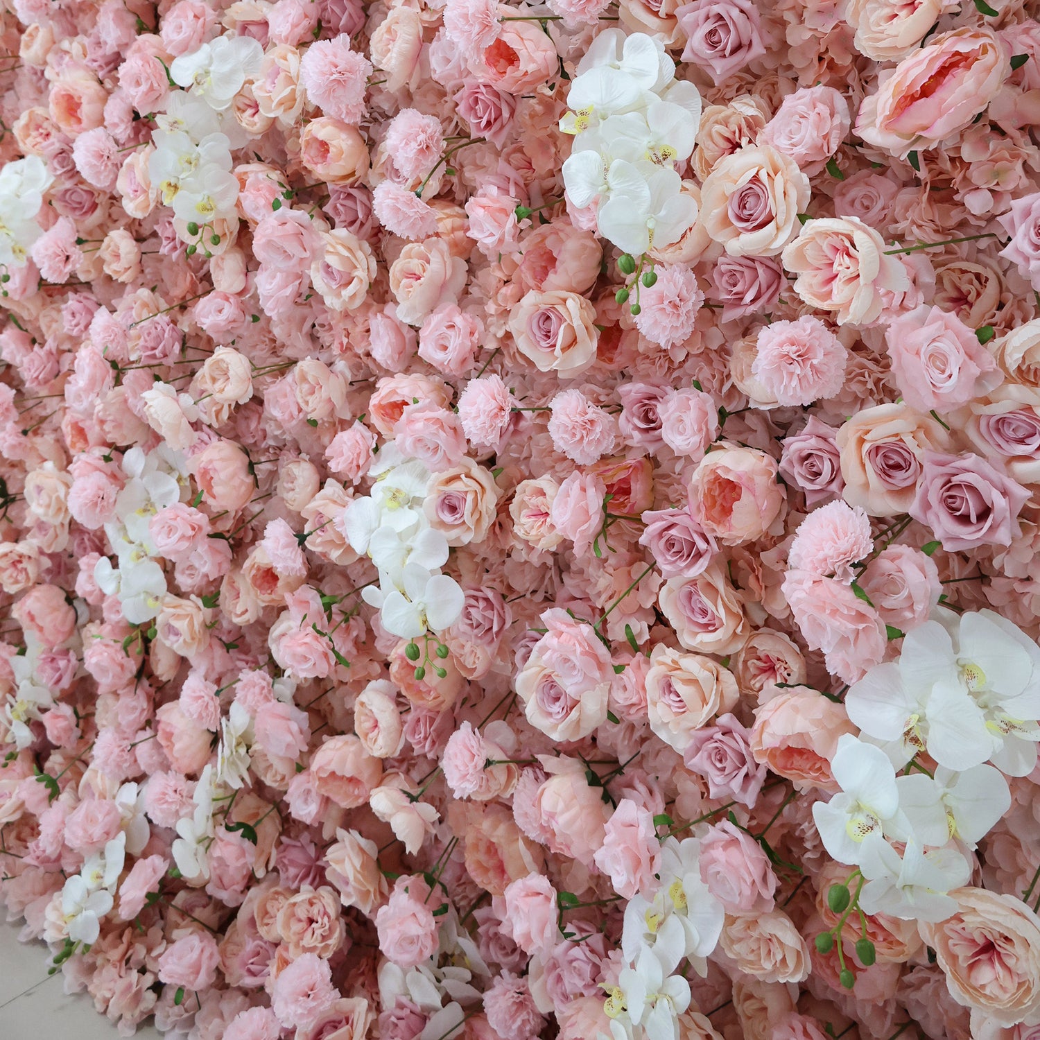 This image showcases a beautiful floral arrangement by Valar Flowers. It features a dense cluster of artificial flowers in soft, romantic shades of pink and white. The blooms, including roses and other complementary flowers, are intricately arranged to create a lush, textured, and visually appealing display. Perfect for adding a touch of elegance and charm to events or spaces, the arrangement exudes a delicate and sophisticated atmosphere.