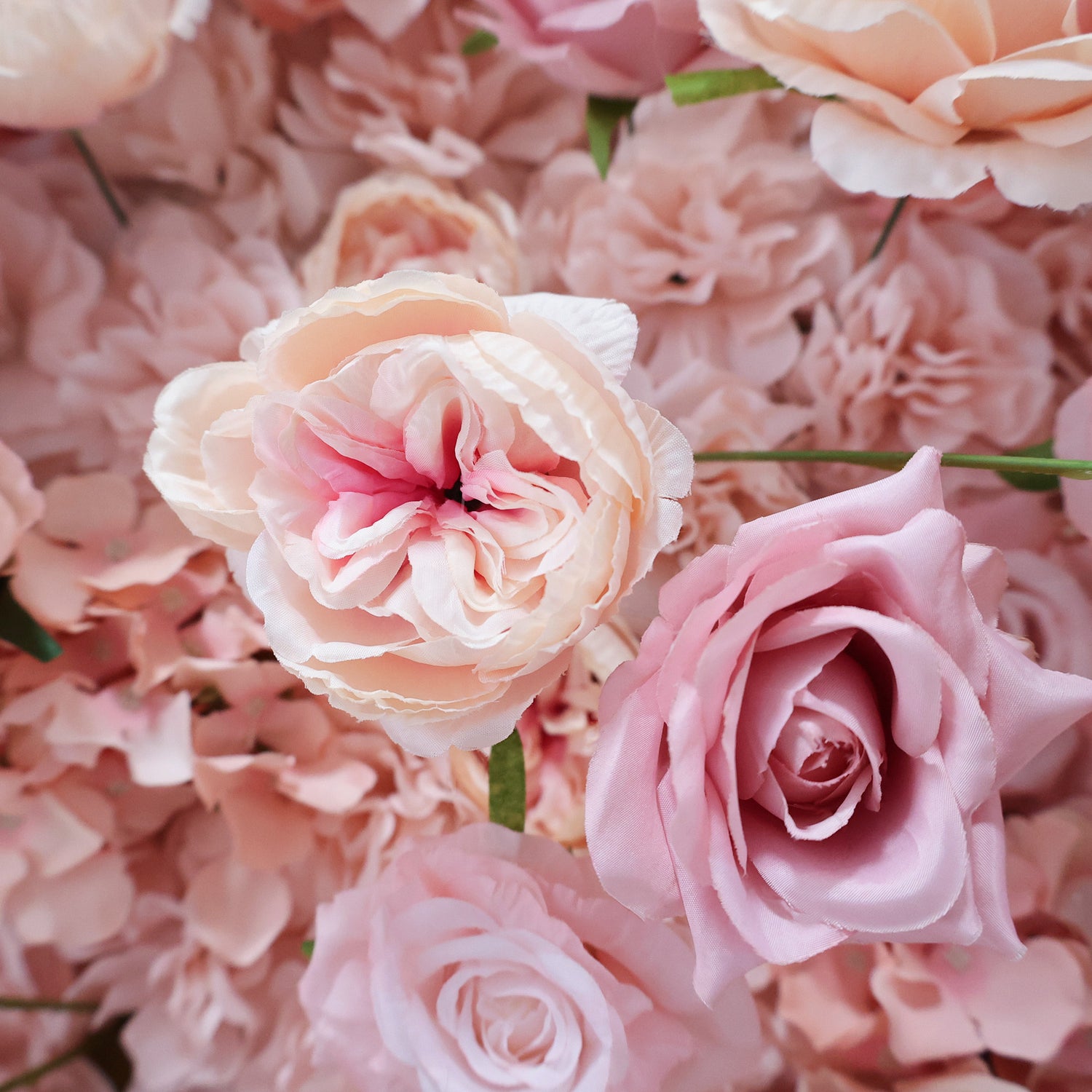 This image showcases a beautiful floral arrangement by Valar Flowers. It features a dense cluster of artificial flowers in soft, romantic shades of pink and peach. The blooms, including roses and other complementary flowers, are intricately arranged to create a lush, textured, and visually appealing display. Perfect for adding a touch of elegance and charm to events or spaces, the arrangement exudes a delicate and sophisticated atmosphere.