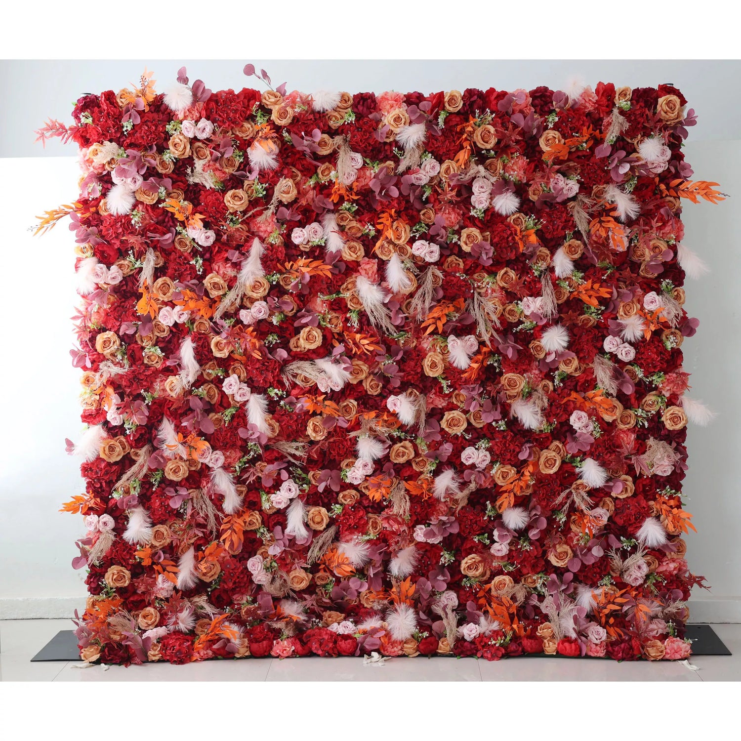 This flower wall is a striking composition, densely packed with a variety of artificial flowers. The dominant red hues blend with accents of pink, orange, and touches of white fluffy elements and foliage. The rich color palette and diverse textures create a warm, passionate atmosphere, making it an ideal backdrop for weddings, events, or photo - shoots, exuding both elegance and a sense of grandeur.