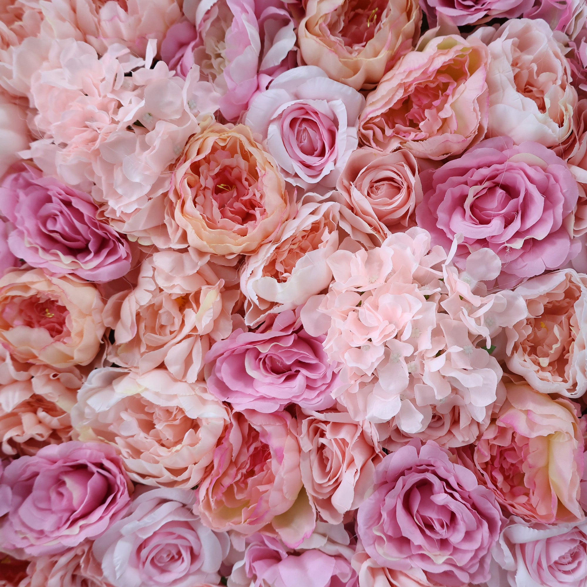 This image showcases a dense arrangement of artificial flowers in various shades of pink, including roses and hydrangeas. The soft, textured petals create a lush, elegant display, ideal for a luxurious, nature-inspired backdrop, likely by ValarFlowers, perfect for adding sophistication to events or interiors.