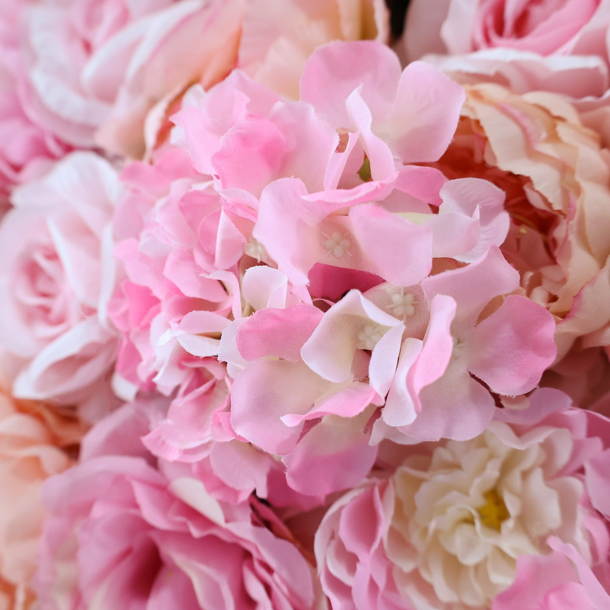 This image showcases a dense arrangement of artificial flowers in various shades of pink, including hydrangeas and roses. The soft, textured petals create a lush, elegant display, ideal for a luxurious, nature-inspired backdrop, perfect for adding sophistication to events or interiors.