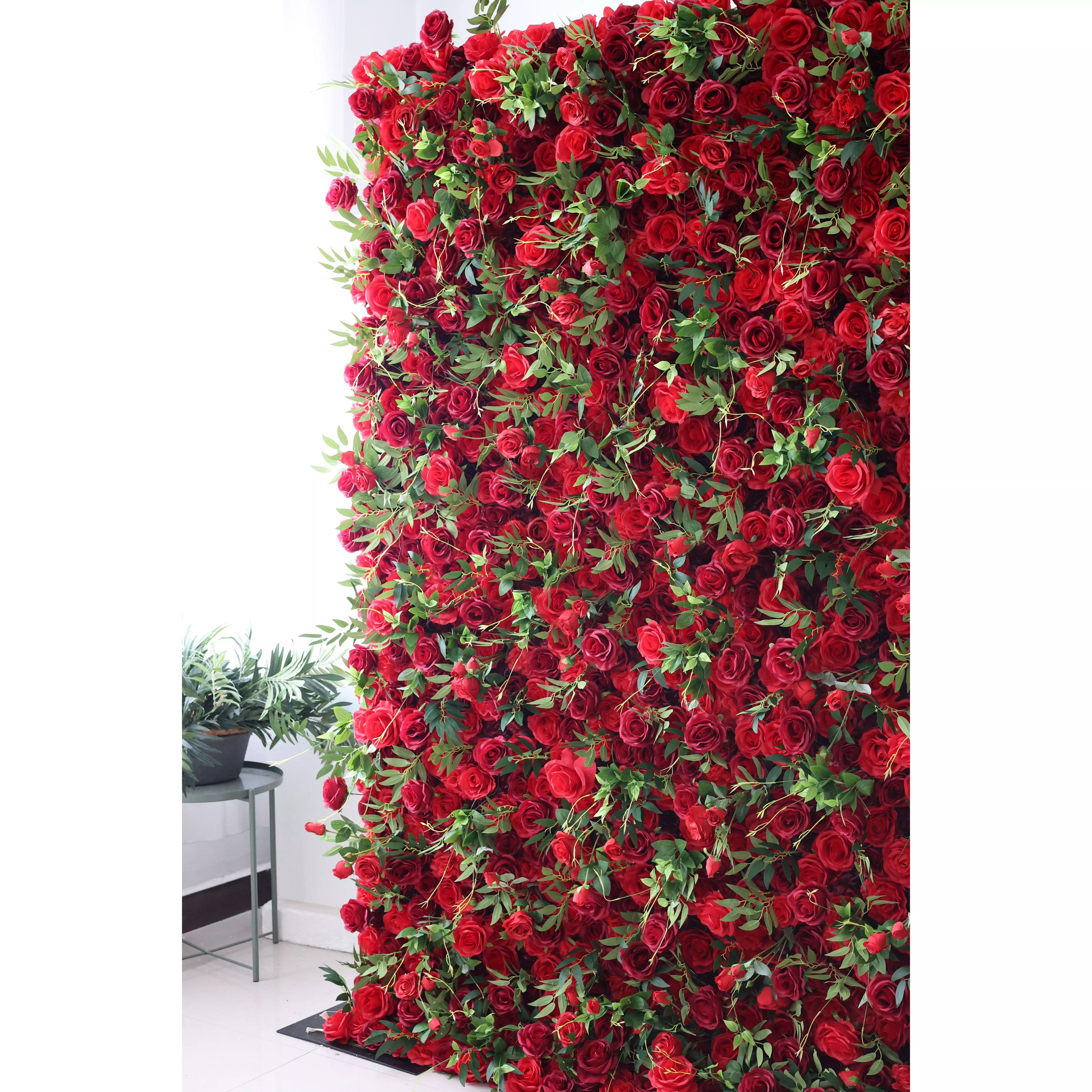 This flower wall features a dense arrangement of artificial red roses, interspersed with lush green leaves. The deep red blooms create a passionate, romantic texture, while the foliage adds freshness. Perfect for weddings or events, it exudes elegance and intensity, serving as a striking backdrop for photos and decor.