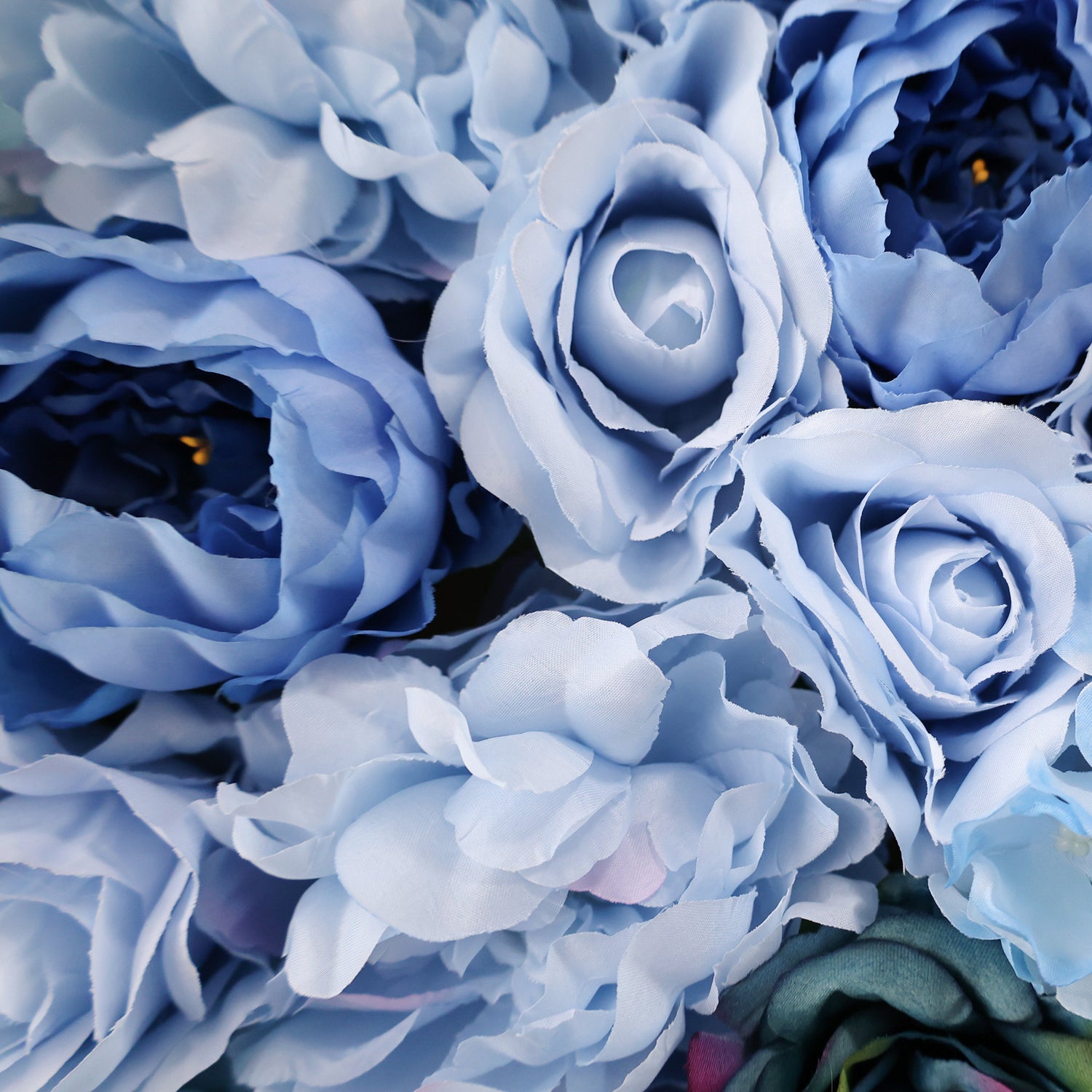 This image showcases a dense arrangement of artificial flowers in various shades of blue, including roses and peonies. The soft, textured petals in hues from light sky blue to deep navy create a lush, elegant display, ideal for a luxurious, nature-inspired backdrop, likely by ValarFlowers, perfect for events or interiors.