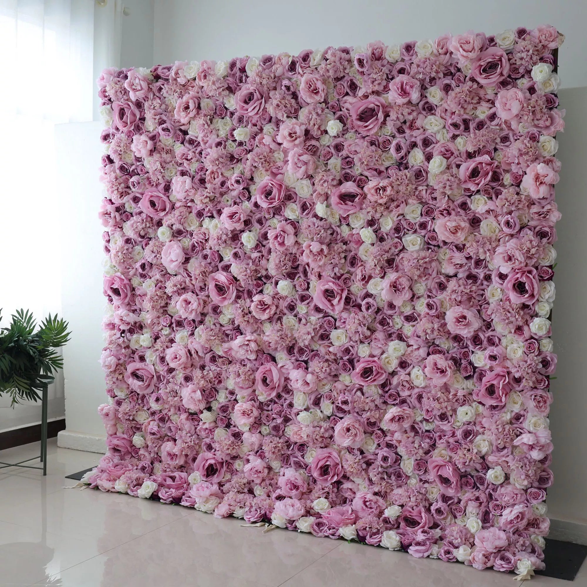 A large floral wall decor featuring a mix of purple and white artificial silk flowers mounted on a fabric cloth backdrop.