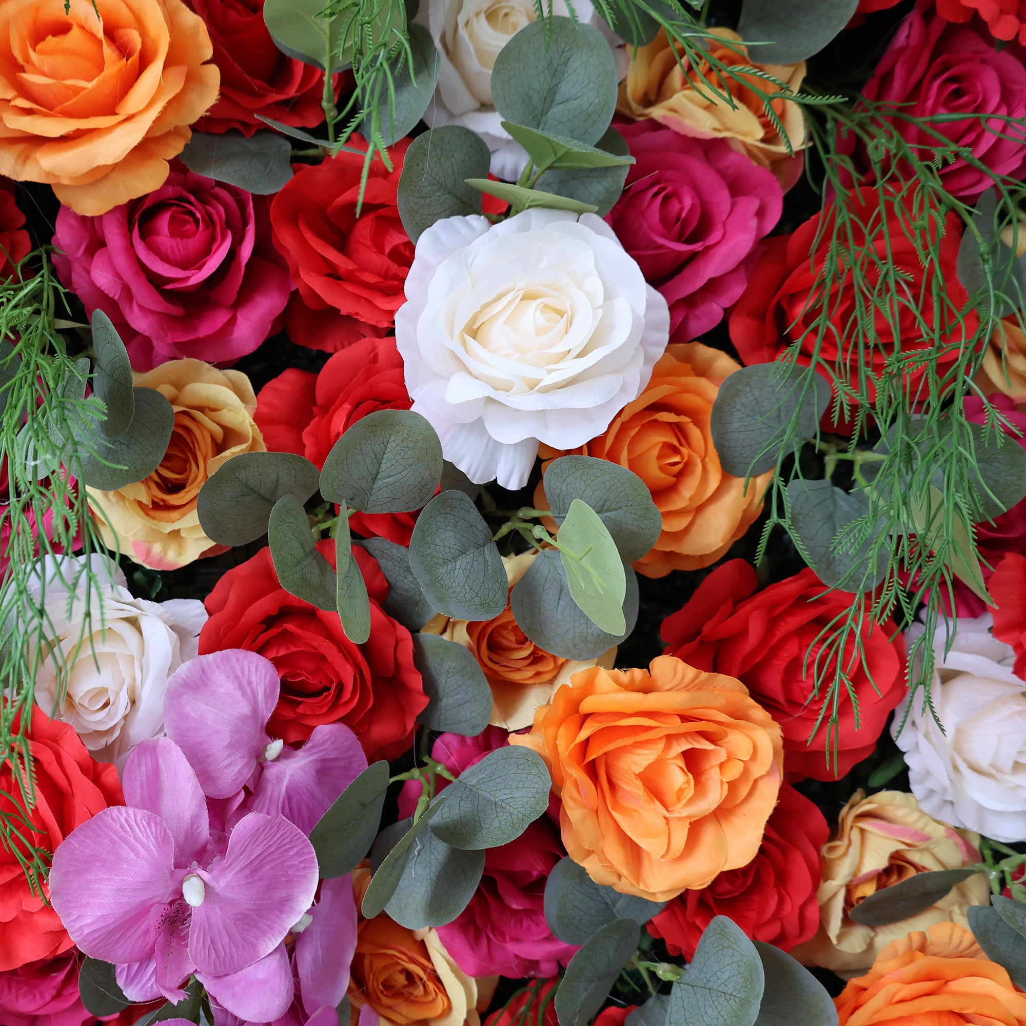 This image showcases a vibrant floral arrangement by Valar Flowers. It features a dense cluster of artificial flowers in a rich palette of red, orange, pink, white, and other complementary hues. The blooms, including roses and orchids, are intricately arranged with lush green foliage, creating a lush, textured, and visually striking display. Perfect for adding a touch of energy and elegance to events or spaces, the arrangement exudes a lively and sophisticated atmosphere.