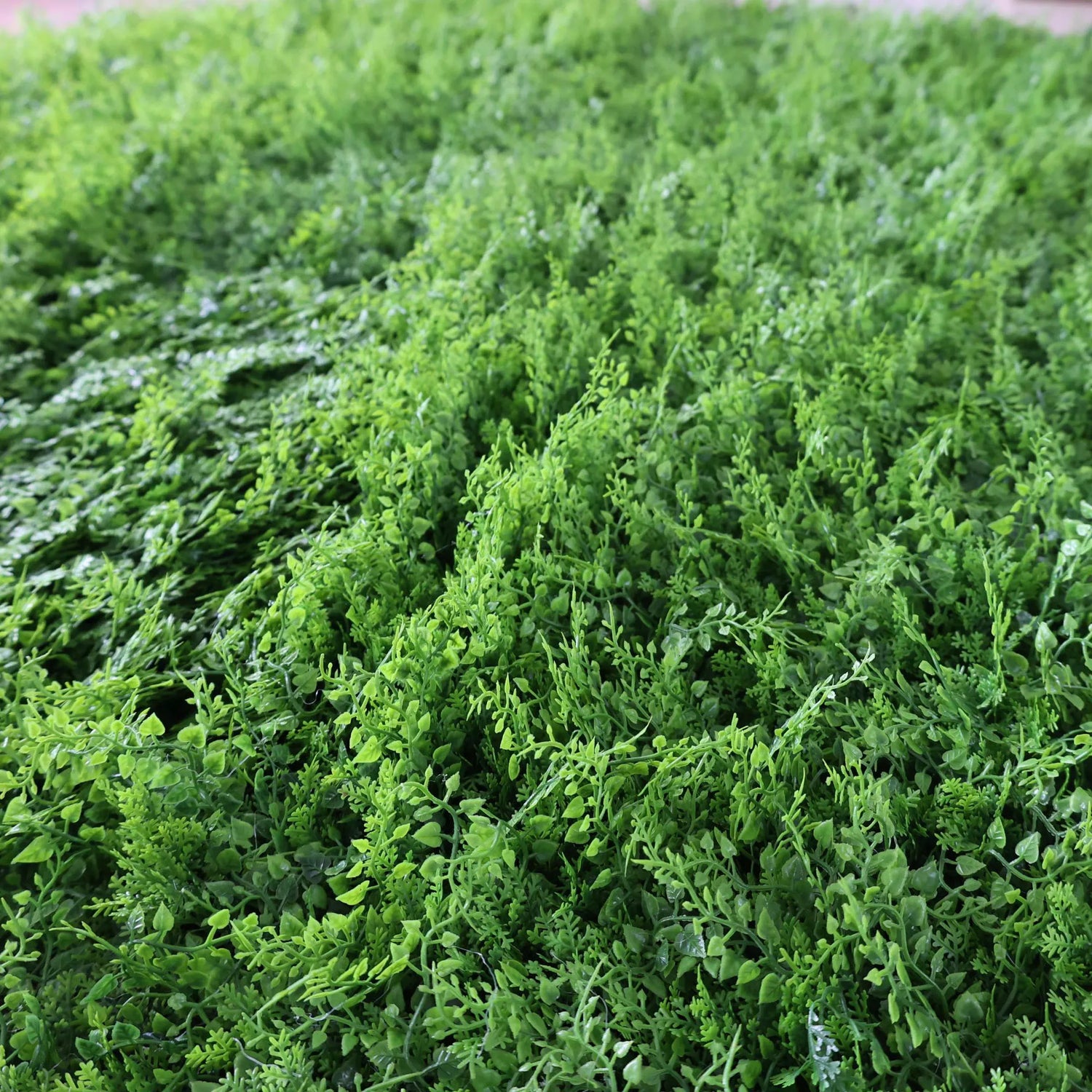 This image showcases a dense artificial greenery product by ValarFlowers. It features a variety of textured green foliage, creating a rich, natural, and visually refreshing display. The lush, varied leaves and stems mimic the look of real greenery, making it perfect for adding a touch of organic elegance to events or spaces. This piece exudes a serene and sophisticated atmosphere, characteristic of ValarFlowers’ attention to detail and craftsmanship.