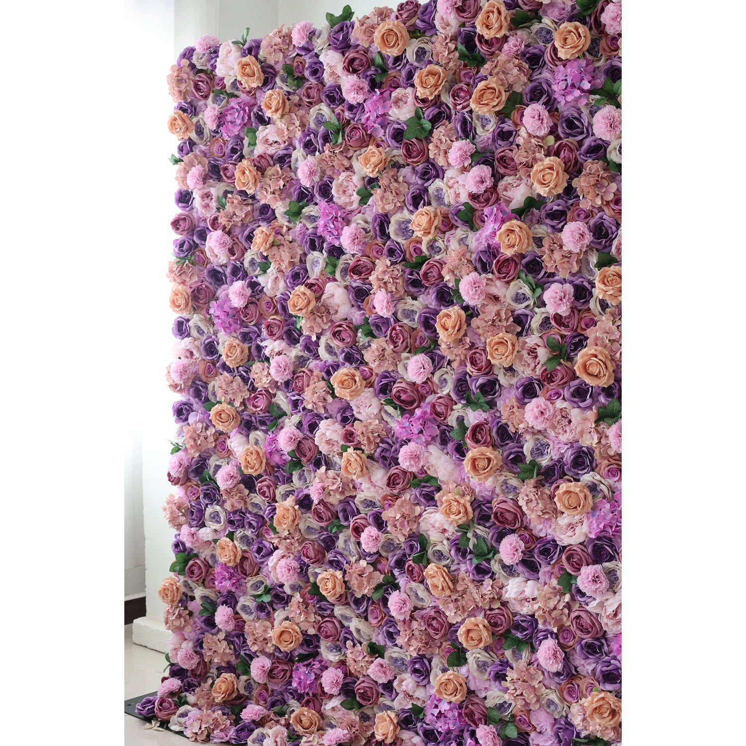 This flower wall is a lush, vibrant display of artificial blooms. A harmonious blend of purple, lavender, and peach roses, plus delicate pink flowers, creates a dreamy, romantic texture. The dense arrangement and soft color palette make it perfect for weddings or elegant events, exuding charm and elegance.