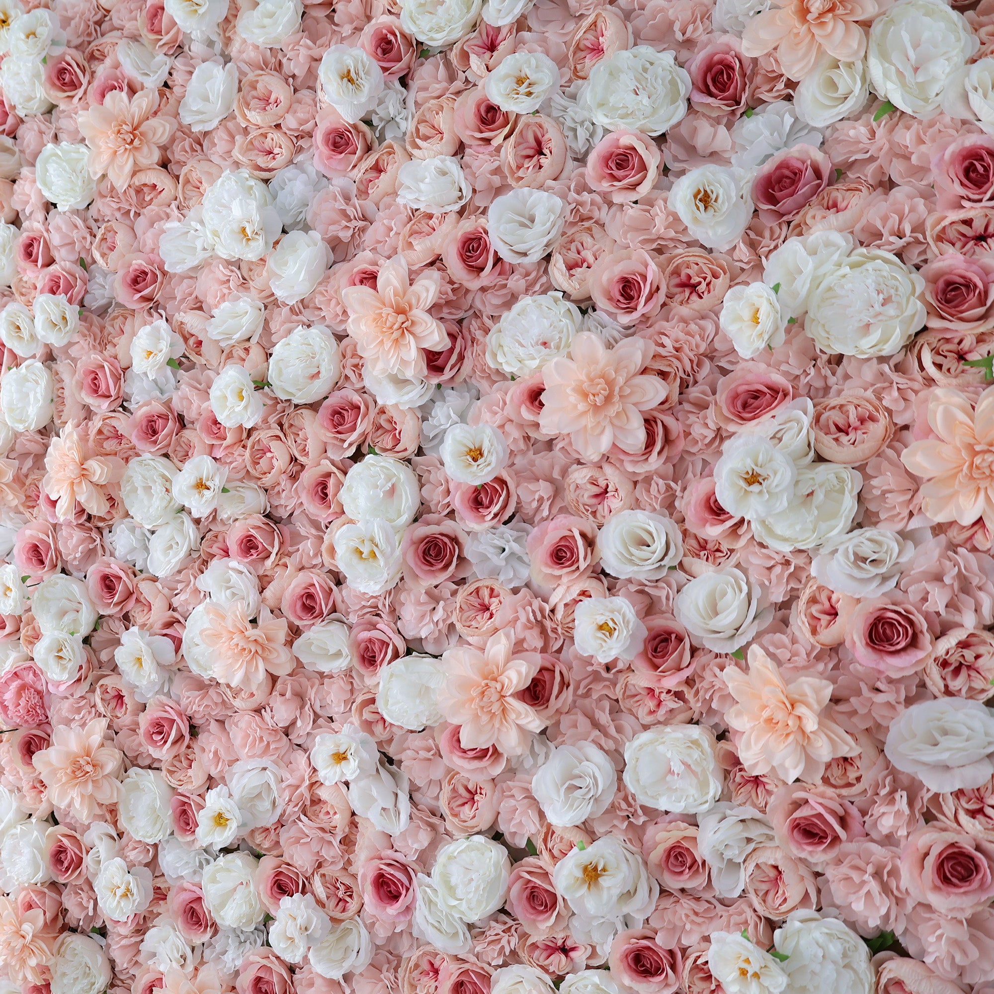 A dense wall of artificial flowers features a lovely mix of pink, blush, and white blooms. Various floral types, including roses and other delicate blossoms, create a lush, romantic display. The soft color palette gives an elegant, charming vibe, perfect for events like weddings or photo backdrops.