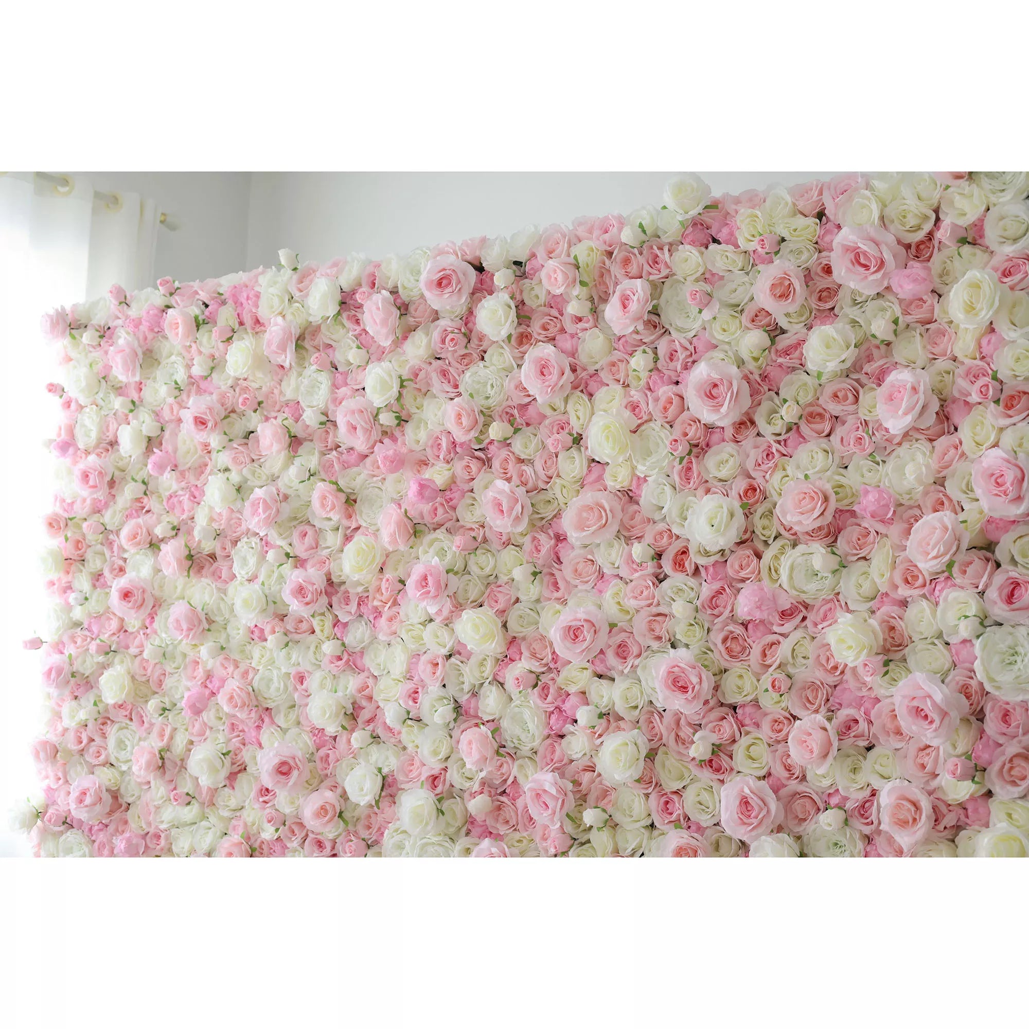 This is a lush, dense artificial flower wall backdrop, overflowing with a rich mix of soft pink, white, and pale green roses and peonies. It fills the frame indoors, with a white curtain visible on the left, creating a romantic, elegant, and dreamy display ideal for weddings, photo shoots, or special events.