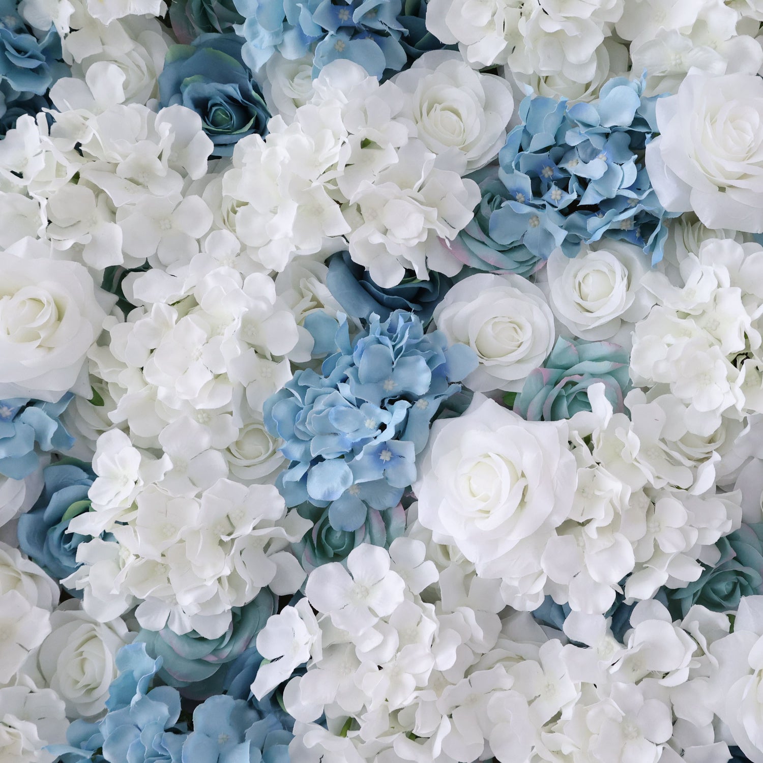 A close - up of artificial flowers showcases a beautiful mix of white and blue blooms. The white flowers, with their soft, layered petals, stand out prominently, while the blue flowers in the background add a cool contrast. The petals have a smooth, slightly glossy texture, giving the flowers a delicate and realistic appearance, ideal for decorative floral arrangements.