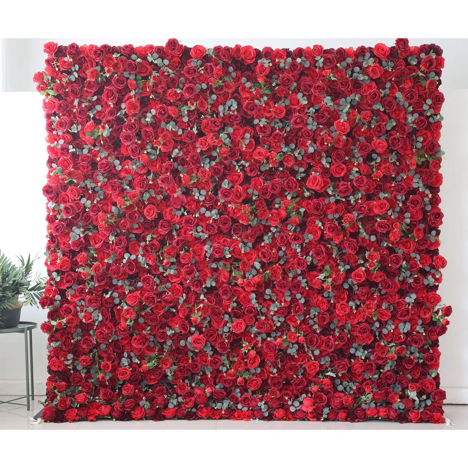 This flower wall is a bold, dense display of artificial red roses with green leaves. The uniform, vibrant red blooms create a striking, passionate texture. Perfect for events needing a dramatic, romantic backdrop, exuding elegance and intensity. A captivating centerpiece for weddings or celebrations.