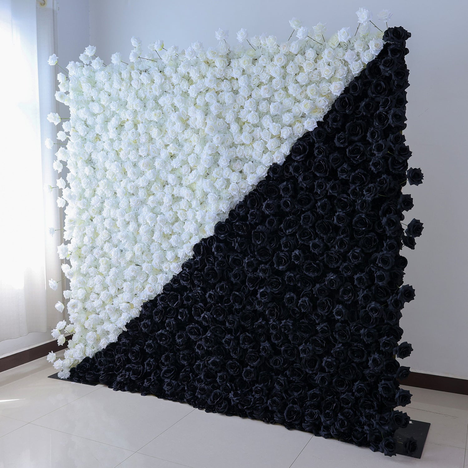This photo showcases a striking floral wall by ValarFlowers, composed entirely of artificial roses. The wall is split diagonally into white and black sections, creating a bold, modern contrast. The uniform texture of the faux roses offers a polished, long - lasting display. Set in an indoor space with a clean, minimalist backdrop, this design makes a dramatic statement. Ideal for avant - garde events, fashion shows, or contemporary decor, it adds a touch of high - contrast elegance