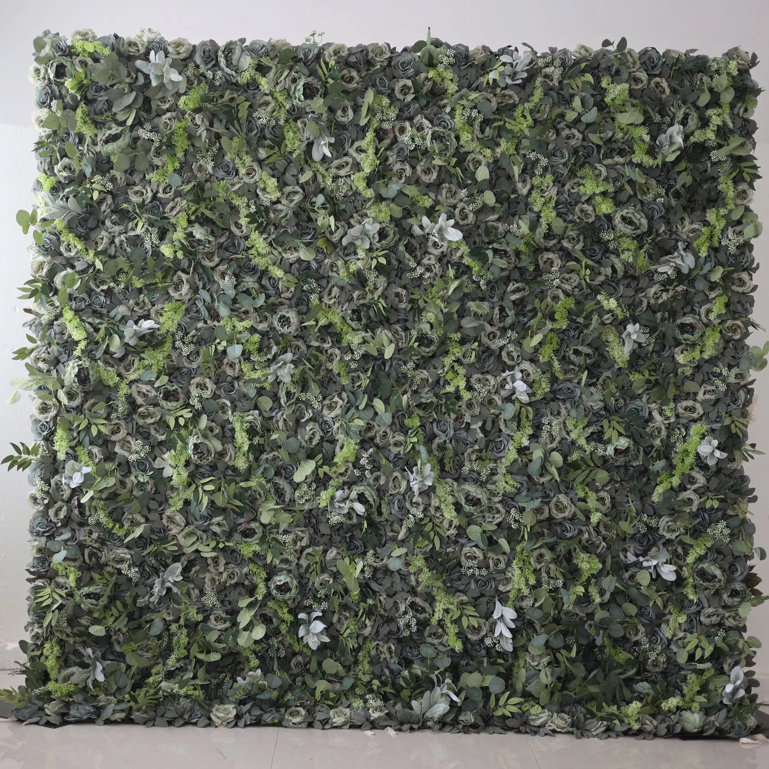 The image shows a lush green wall covered entirely with various types of foliage and flowers. The greenery is dense, with a mix of different shades of green, creating a natural and vibrant appearance.