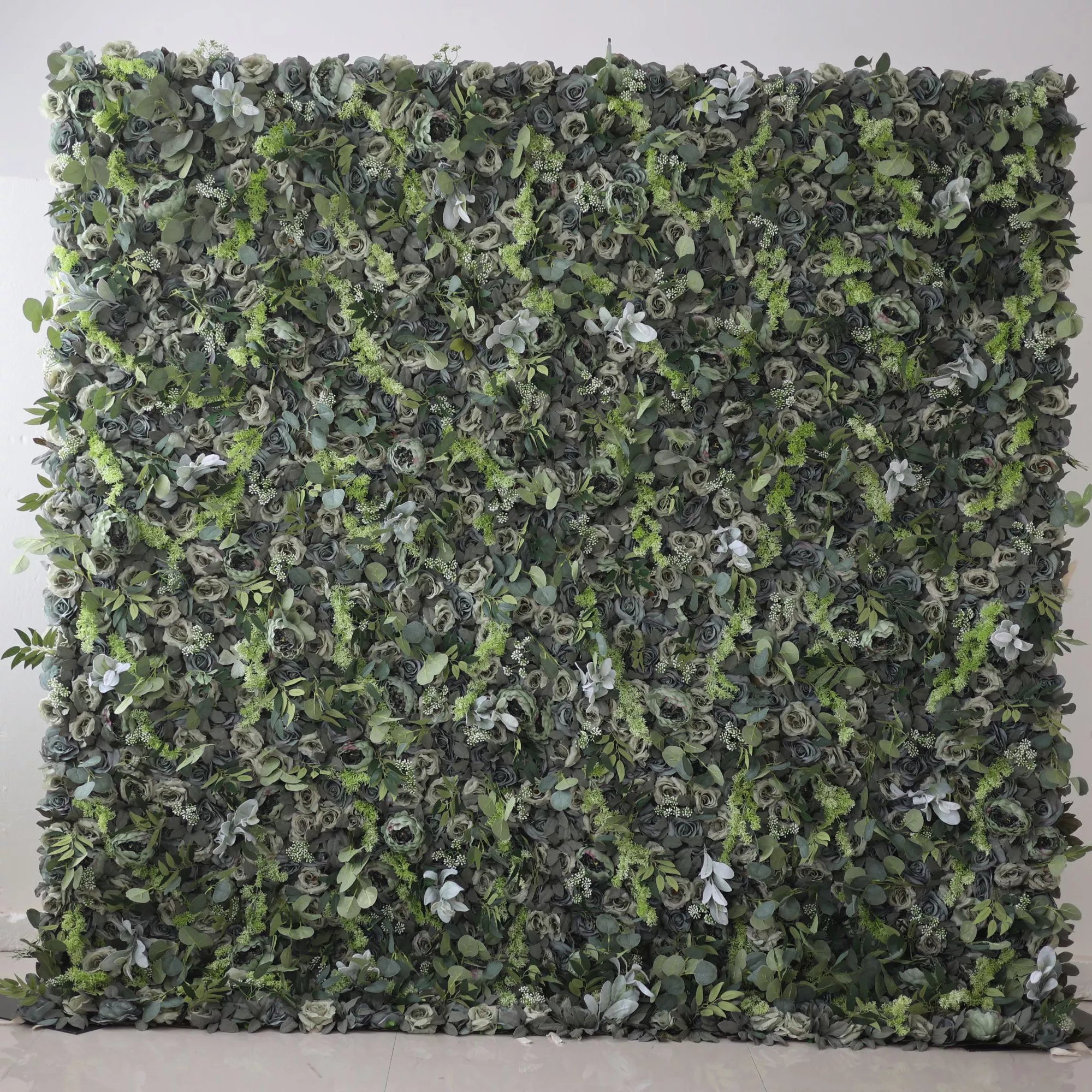 The image shows a lush green wall covered entirely with various types of foliage and flowers. The greenery is dense, with a mix of different shades of green, creating a natural and vibrant appearance.