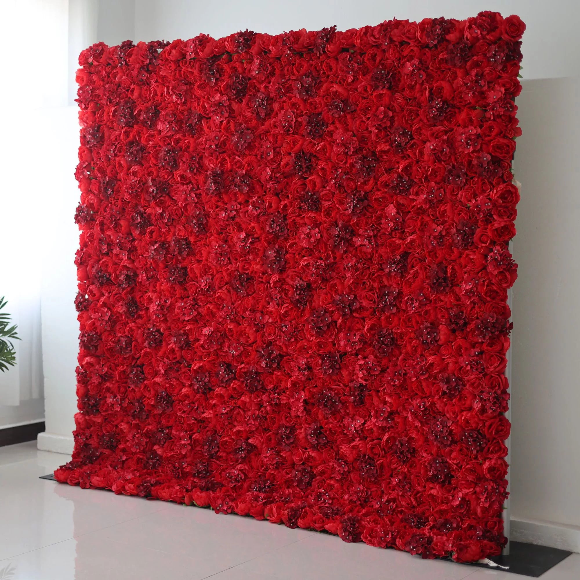 This indoor floral backdrop (set against a minimalist white wall and tiled floor) is a dense, immersive wall of deep red roses, interspersed with subtle, glittering accents that catch the light. The rich, saturated hue and velvety texture create a bold, passionate display, ideal for romantic proposals, Valentine’s Day events, or upscale photo booths seeking a dramatic, eye-catching focal point.