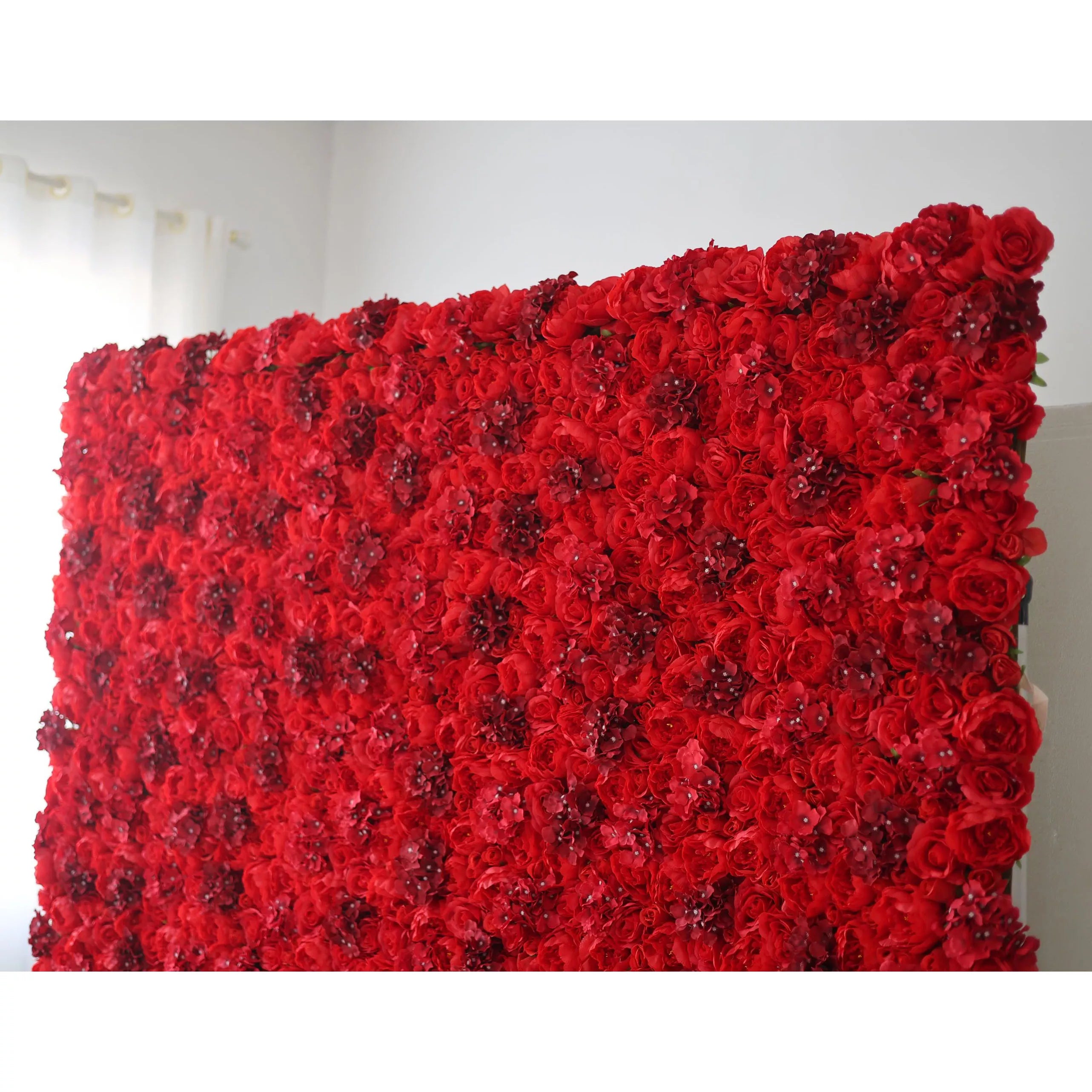 This indoor floral backdrop (set against a minimalist white wall) is a dense, immersive expanse of deep red roses and textured filler blooms, interspersed with subtle, glittering accents that catch the light. The rich, saturated hue and velvety texture create a bold, passionate display, ideal for romantic proposals, Valentine’s Day events, or upscale photo booths seeking a dramatic, eye-catching focal point.