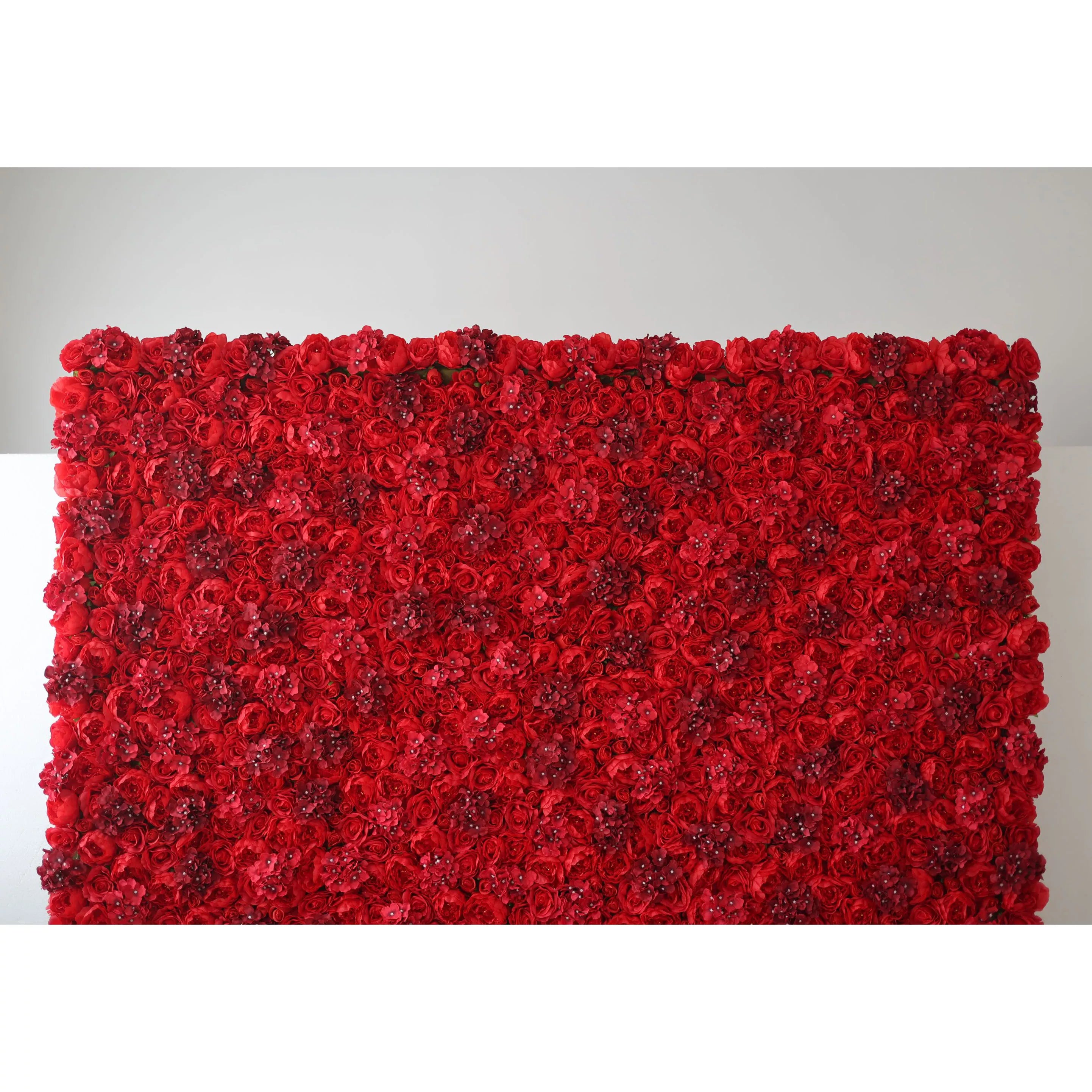This indoor floral backdrop (set against a minimalist white wall) is a dense, immersive expanse of deep red artificial roses and textured filler blooms, interspersed with subtle, glittering accents that catch the light. The rich, saturated hue and velvety texture create a bold, passionate display, ideal for romantic proposals, Valentine’s Day events, or upscale photo booths seeking a dramatic, eye-catching focal point.