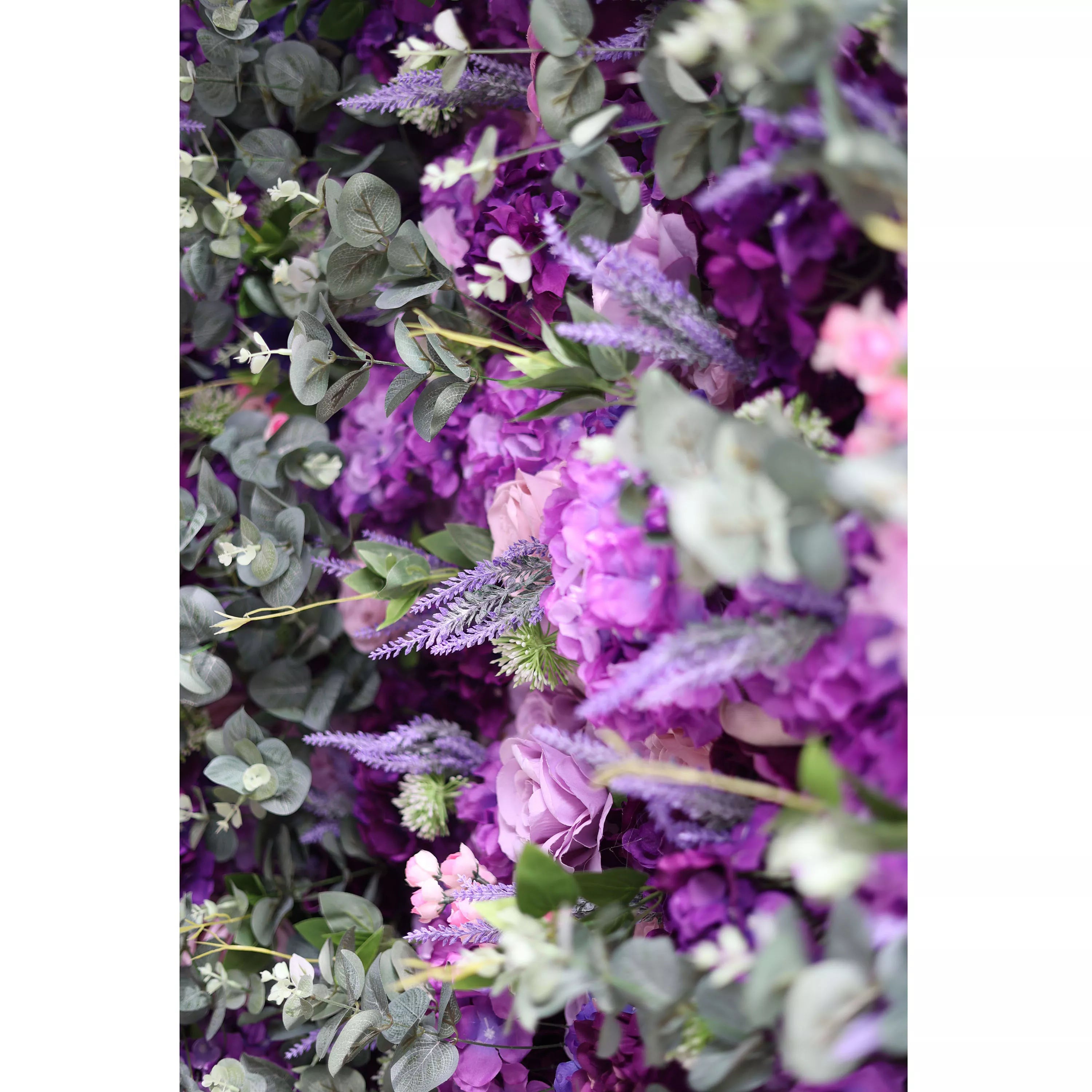 This image showcases a lush arrangement of flowers in various shades of purple, from deep violet to soft lavender, along with hints of pink blooms. Interspersed with green and grayish leaves, the dense cluster creates a rich, vibrant, and elegant visual. The combination of petals and foliage gives a sense of natural abundance and beauty, making it a perfect decorative element for events or as a stunning backdrop.