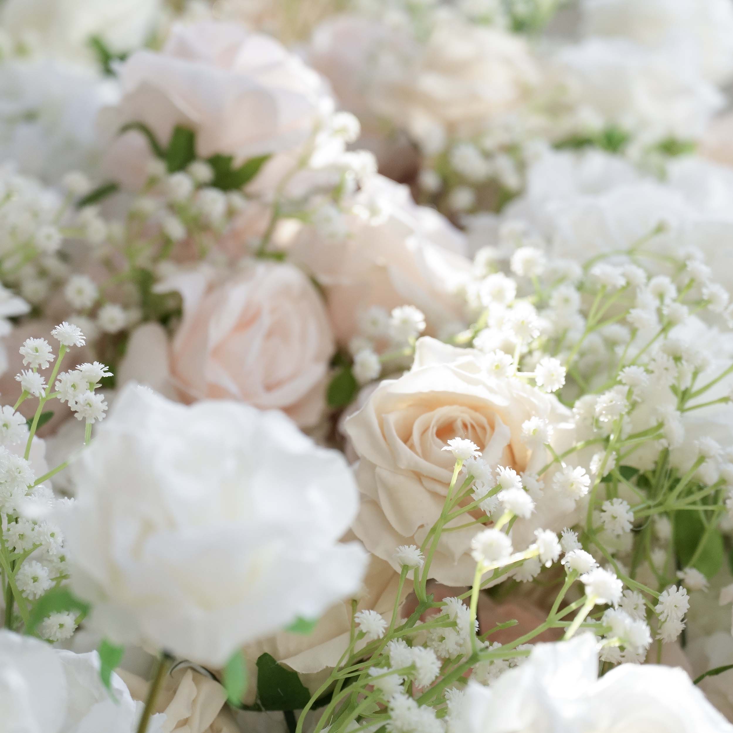 This close - up showcases a lush arrangement of artificial flowers. Prominently featured are roses in soft, pastel hues like light pink, cream, and white, interspersed with delicate sprigs of baby&