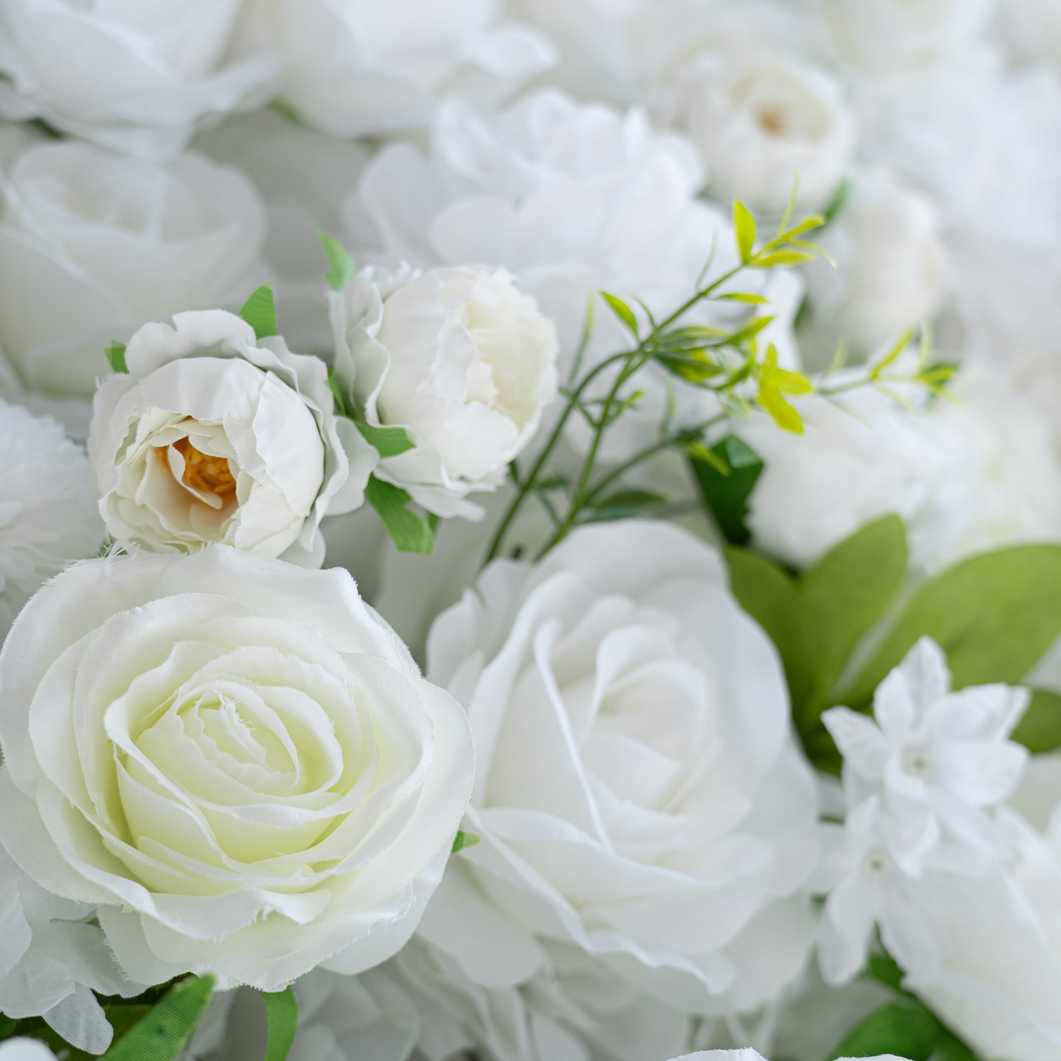 This close - up showcases a lush arrangement of artificial white flowers. Prominently featured are roses in various forms, accompanied by other white blooms like small - petaled flowers. Interspersed with green leaves, the color palette is a pure white with green accents. The style is elegant and pristine, perfect for formal or romantic events.