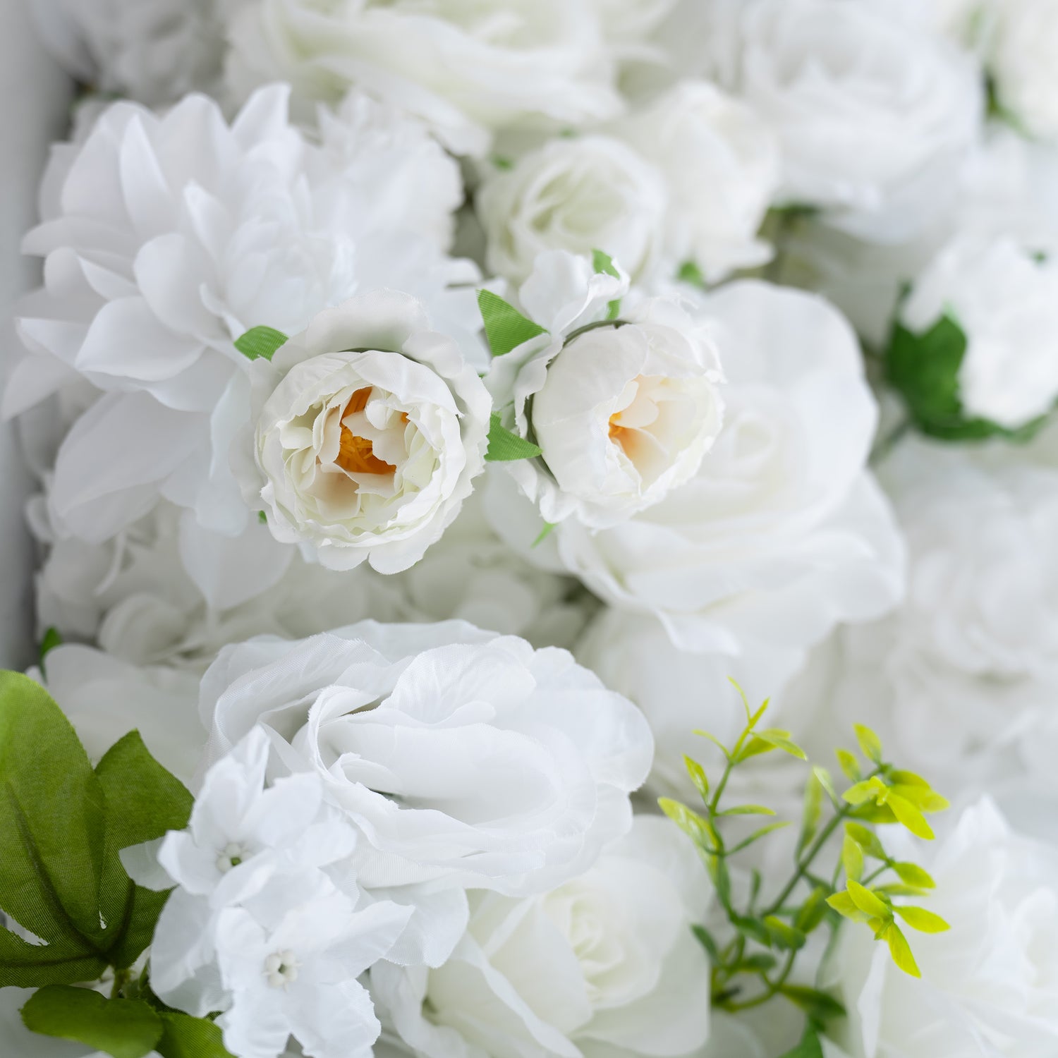 This close - up image features a rich arrangement of artificial white flowers. The main types include roses and peony - like blooms, complemented by small white blossoms and green leaves. The all - white color palette with green accents creates an elegant, clean, and sophisticated style, perfect for formal events.