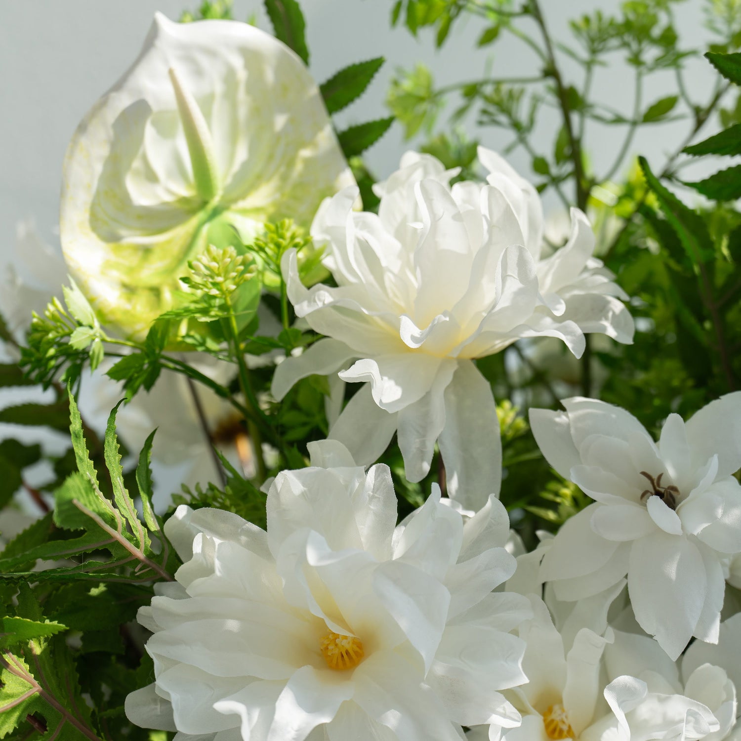 The floral arrangement features a variety of white flowers, including large peonies and calla lilies, surrounded by lush green foliage. This elegant composition is perfect for weddings, creating a romantic and sophisticated atmosphere.