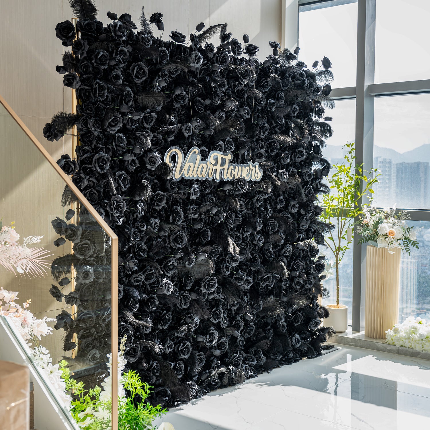The image showcases a luxurious black rose wall with the brand name "ValarFlowers" prominently displayed. The wall is adorned with feathers at the edges, creating a dramatic and elegant atmosphere.