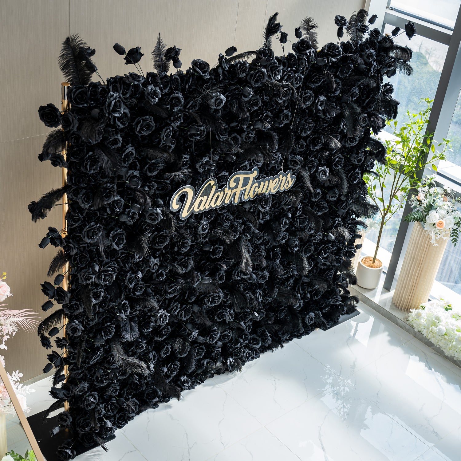 The black rose wall with the "ValarFlowers" sign is suitable for sophisticated weddings, dramatic corporate events, and stylish galas. The dark, romantic ambiance created by the black roses and feathers would enhance the atmosphere of any high - end gathering.