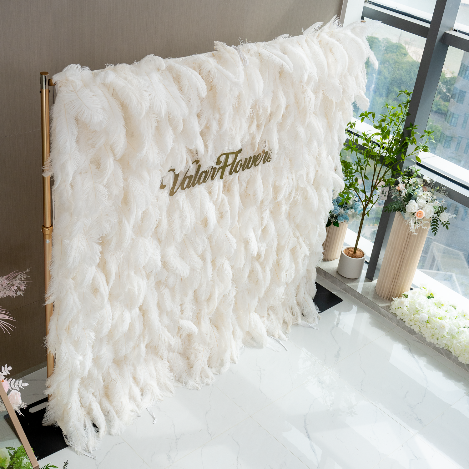 The ValarFlowers artificial feather wall is a luxurious display of white feathers. It has a soft, plush appearance, creating an elegant and dreamy backdrop, perfect for events.