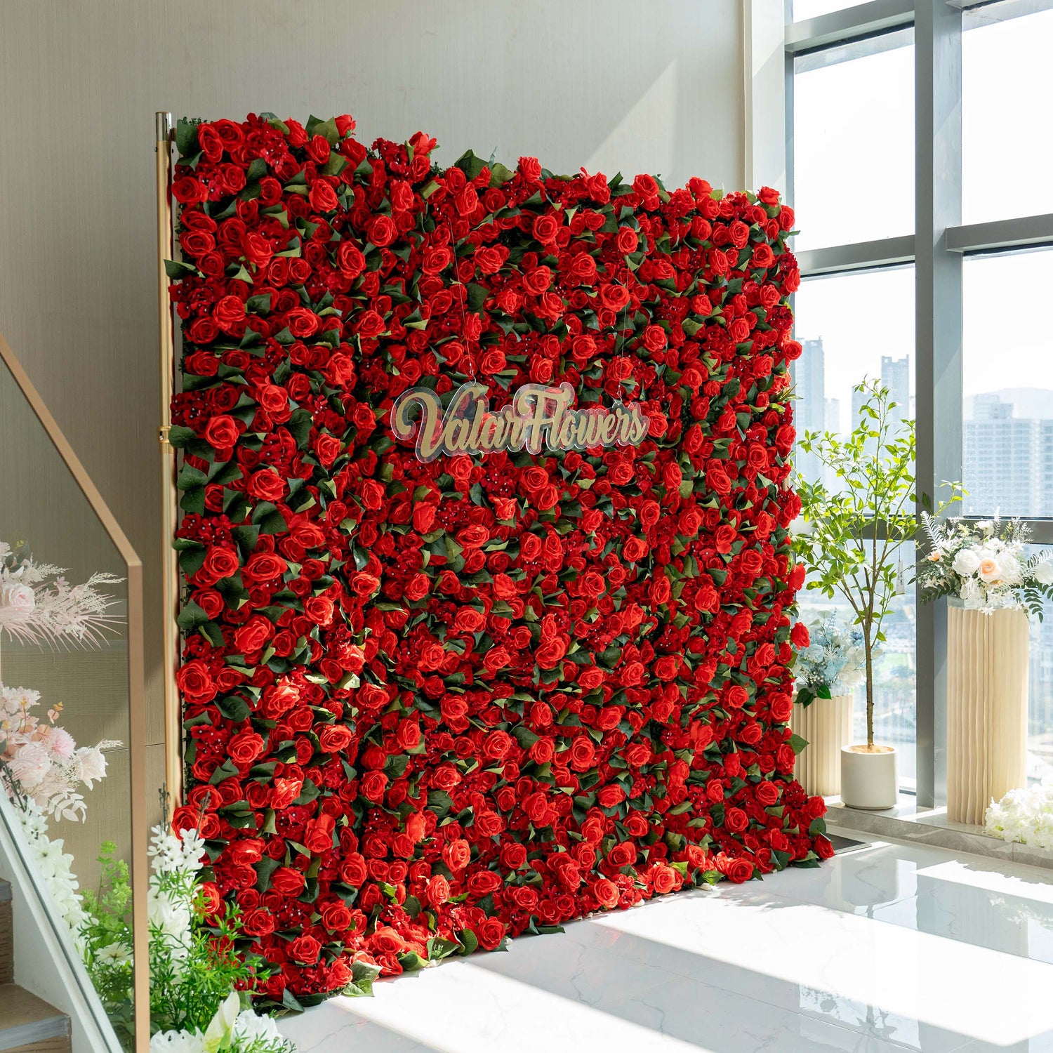 A vibrant red floral wall by ValarFlowers, densely covered with artificial roses, creating a striking and romantic backdrop.