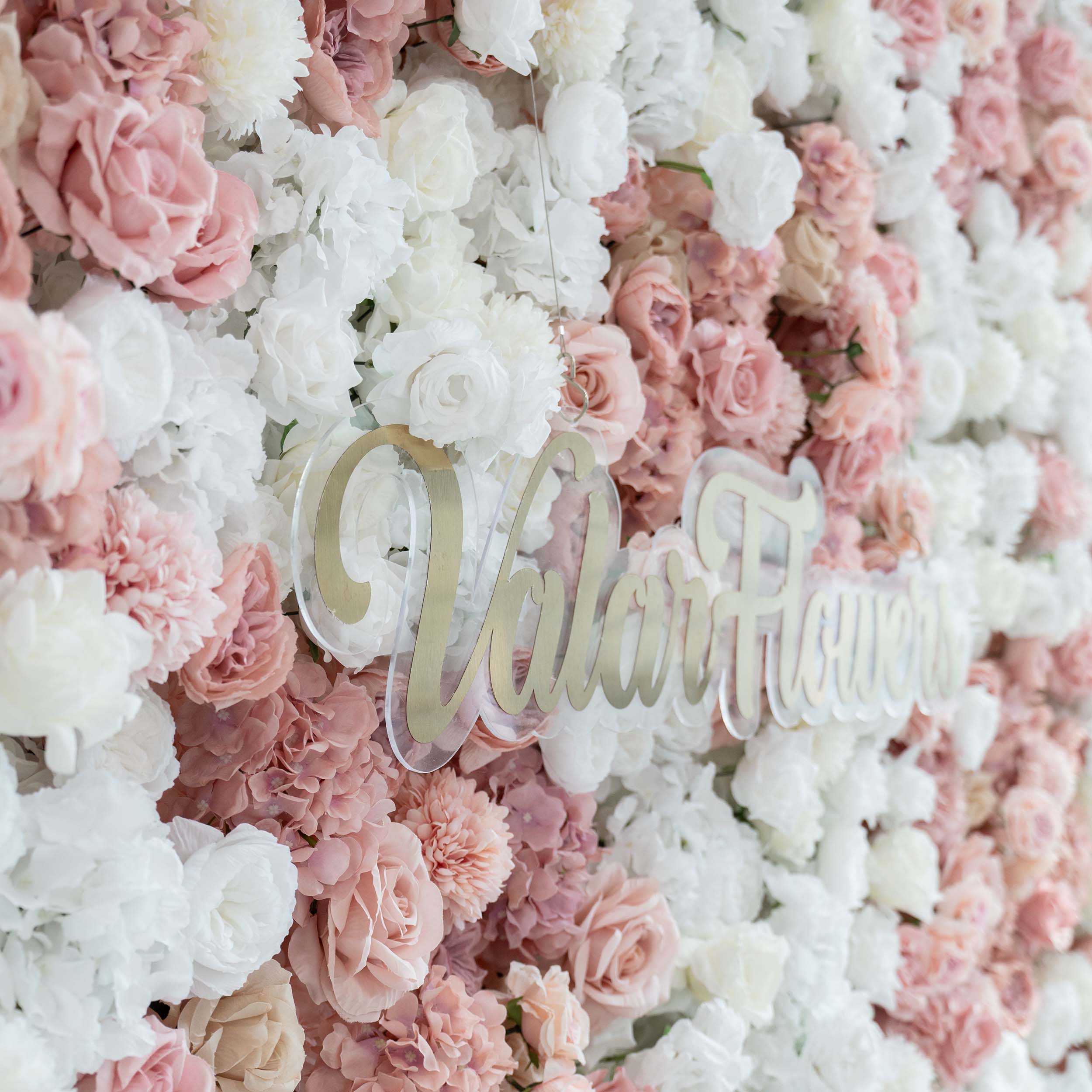 A close - up of a floral wall by ValarFlowers showcases a blend of white and pink artificial roses and hydrangeas, with the brand&