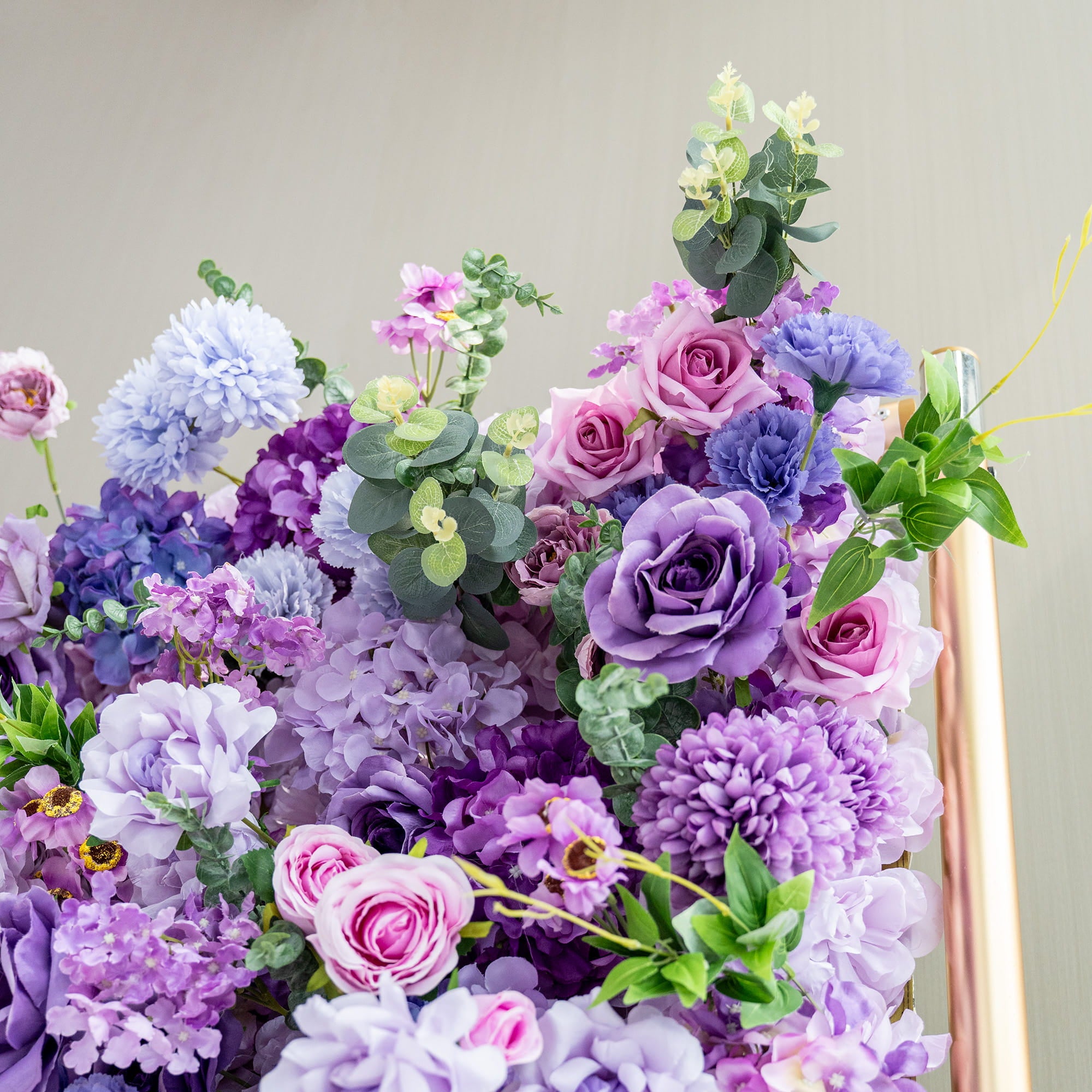 This image features a vibrant floral arrangement with a palette of purple - toned hues, ranging from deep violet to soft lavender and light blue. The flowers include roses, hydrangeas, and chrysanthemum - like blooms. Interspersed green eucalyptus leaves add a fresh touch. The overall style is lush and romantic, creating a dreamy and visually appealing display, perfect for events or decorative backdrops.