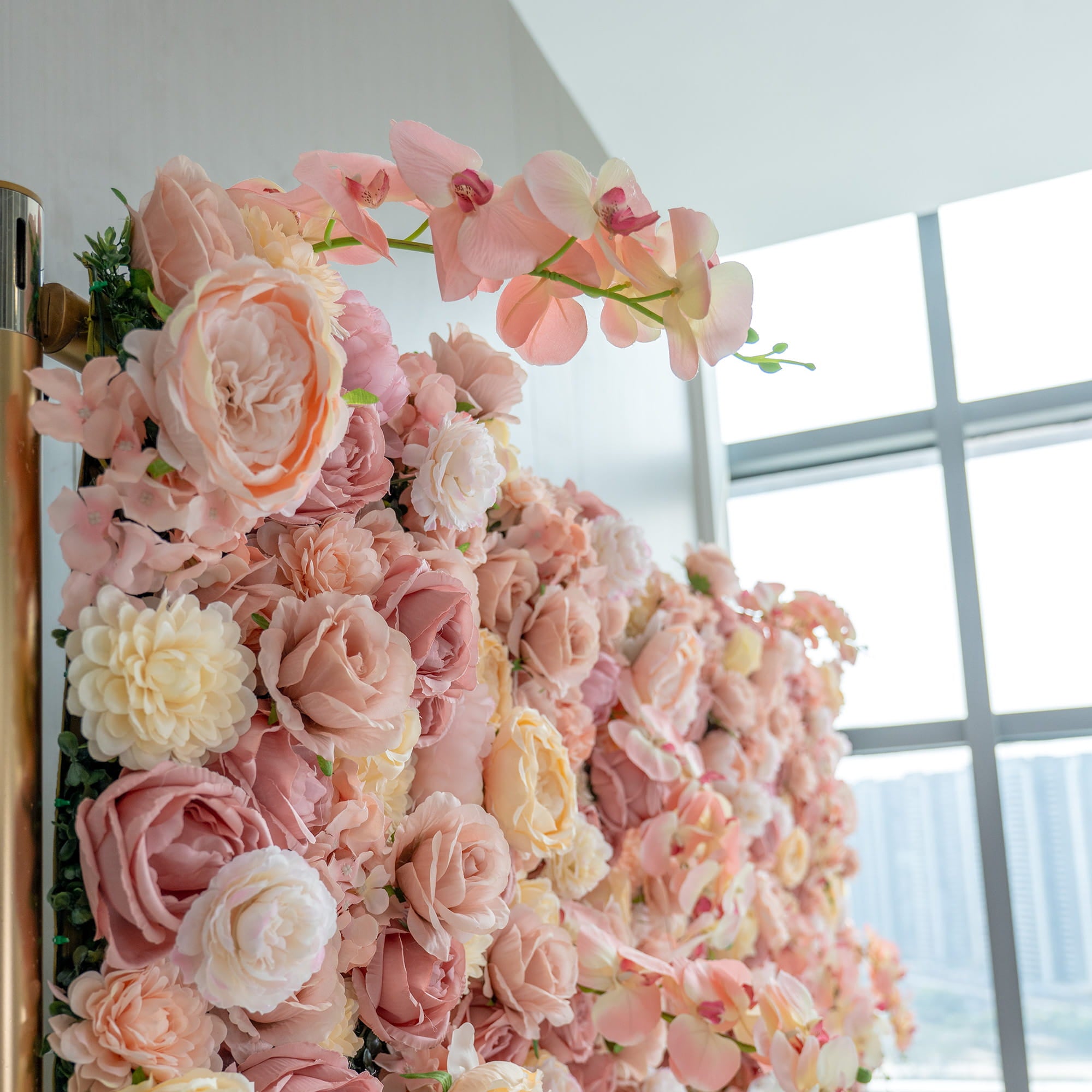 This image shows a section of a flower wall with artificial roses, peonies, dahlias, and orchids in soft pastel pinks and creams. There&