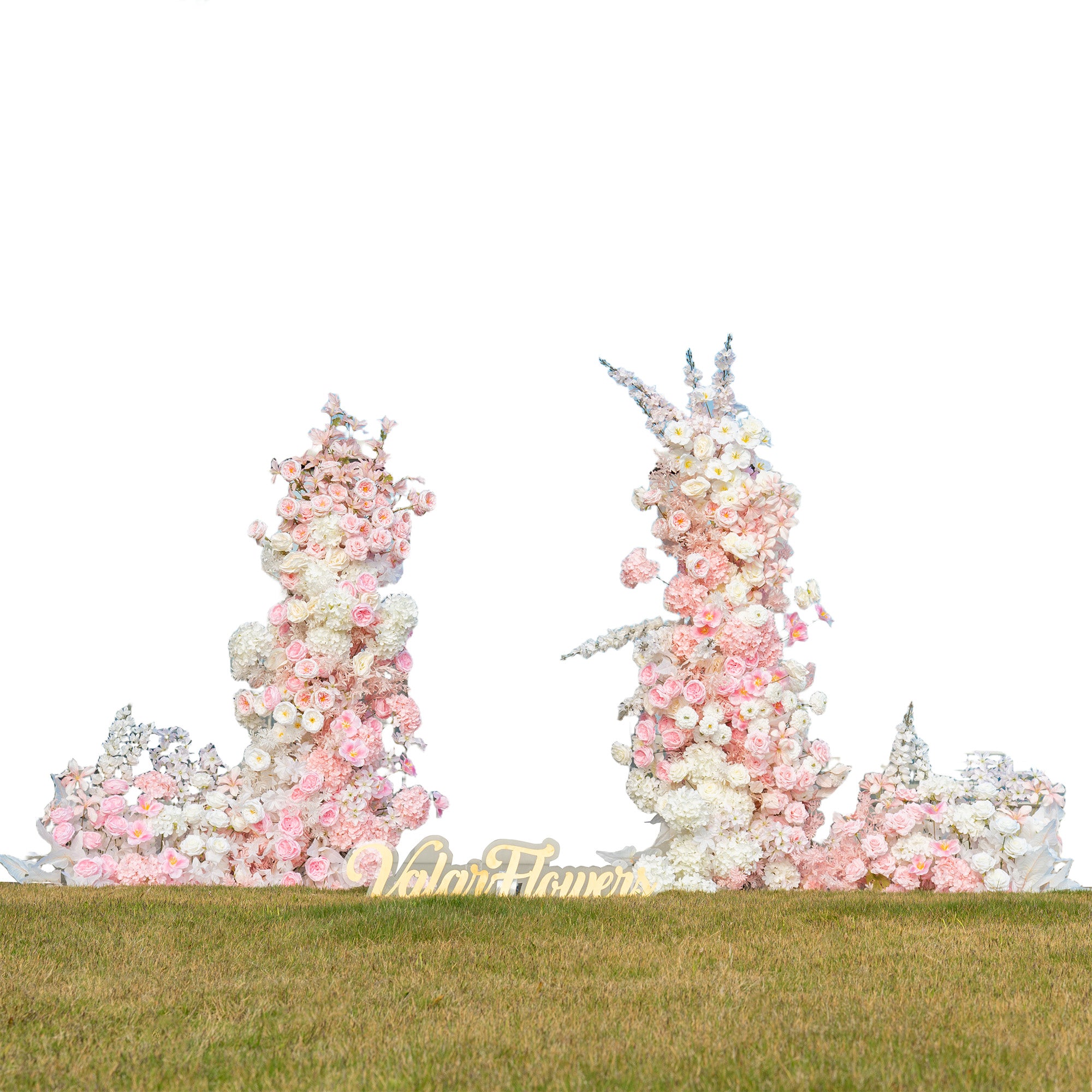 This backdrop consists of two tall floral structures placed on a grassy area. The arrangements feature a mix of artificial flowers, including pink and white roses, white hydrangeas, and delicate pink blossoms. The color palette is soft, with pastel - toned pinks and whites, creating a romantic and elegant style, perfect for wedding ceremonies. The "ValarFlowers" sign adds a touch of branding.