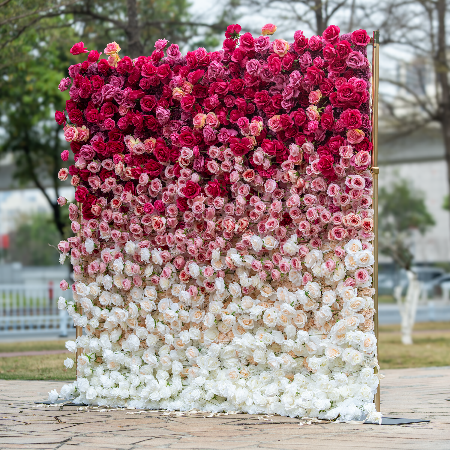 This backdrop showcases a stunning 8x8ft arrangement of artificial roses in a gradient from deep red at the top to soft white at the bottom. Set on a golden stand, it creates a luxurious and romantic atmosphere, ideal for weddings or special events.