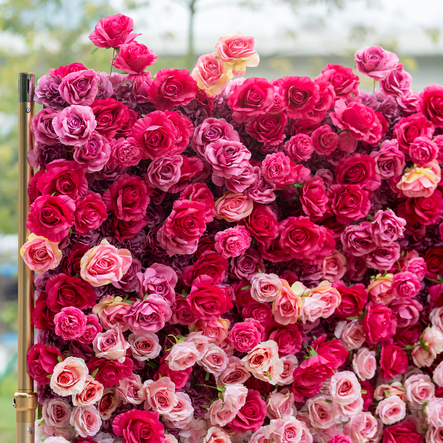 This backdrop is a lush expanse of artificial roses in a vivid blend of deep red and pink hues, creating a rich, romantic tapestry. The densely packed blooms, with some showing soft gradients, exude luxury, perfect for high - end events or weddings.