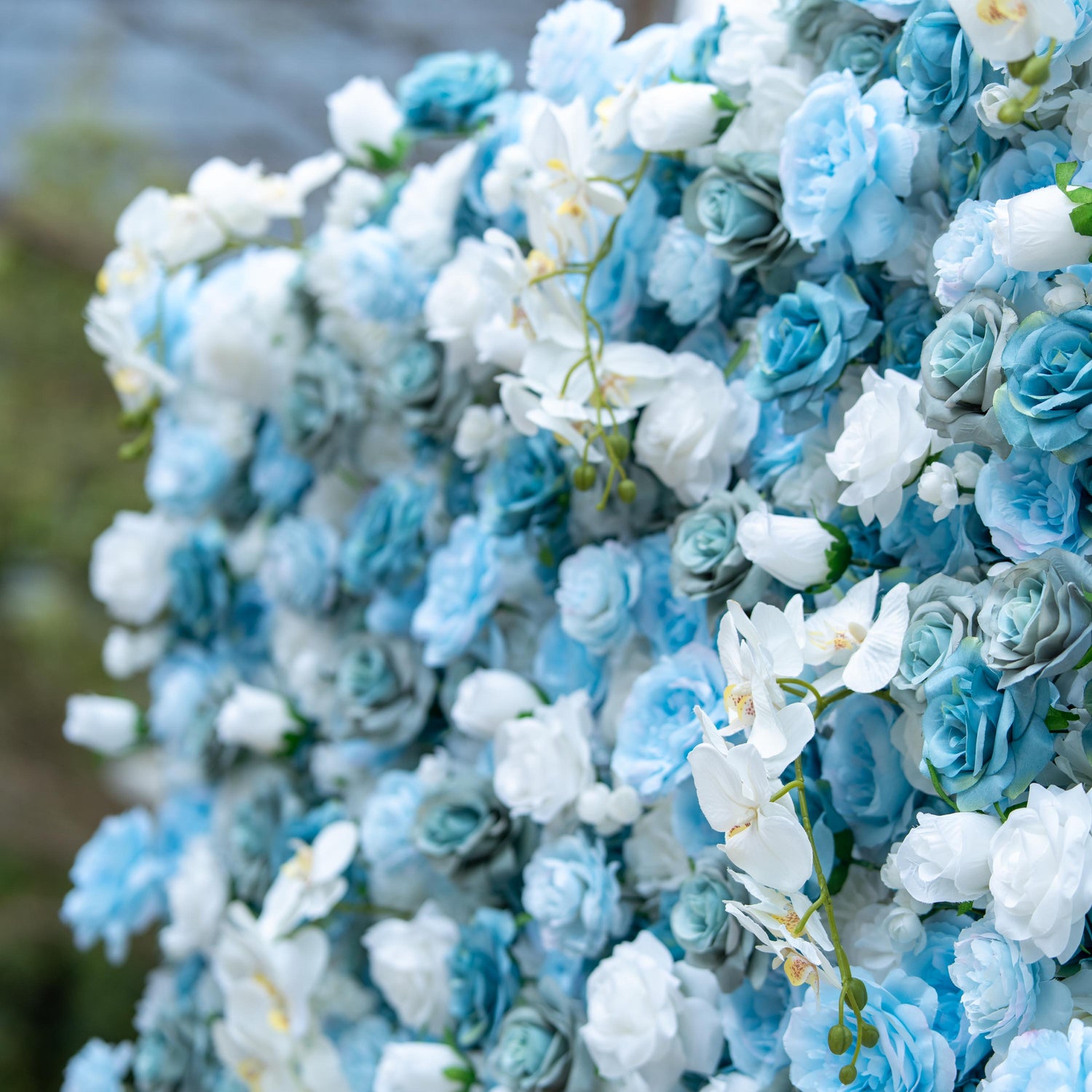 This photo showcases a lush floral arrangement featuring a beautiful blend of blue and white roses, complemented by elegant white orchids. The varying shades of blue and white create a visually soothing and harmonious effect. The roses&