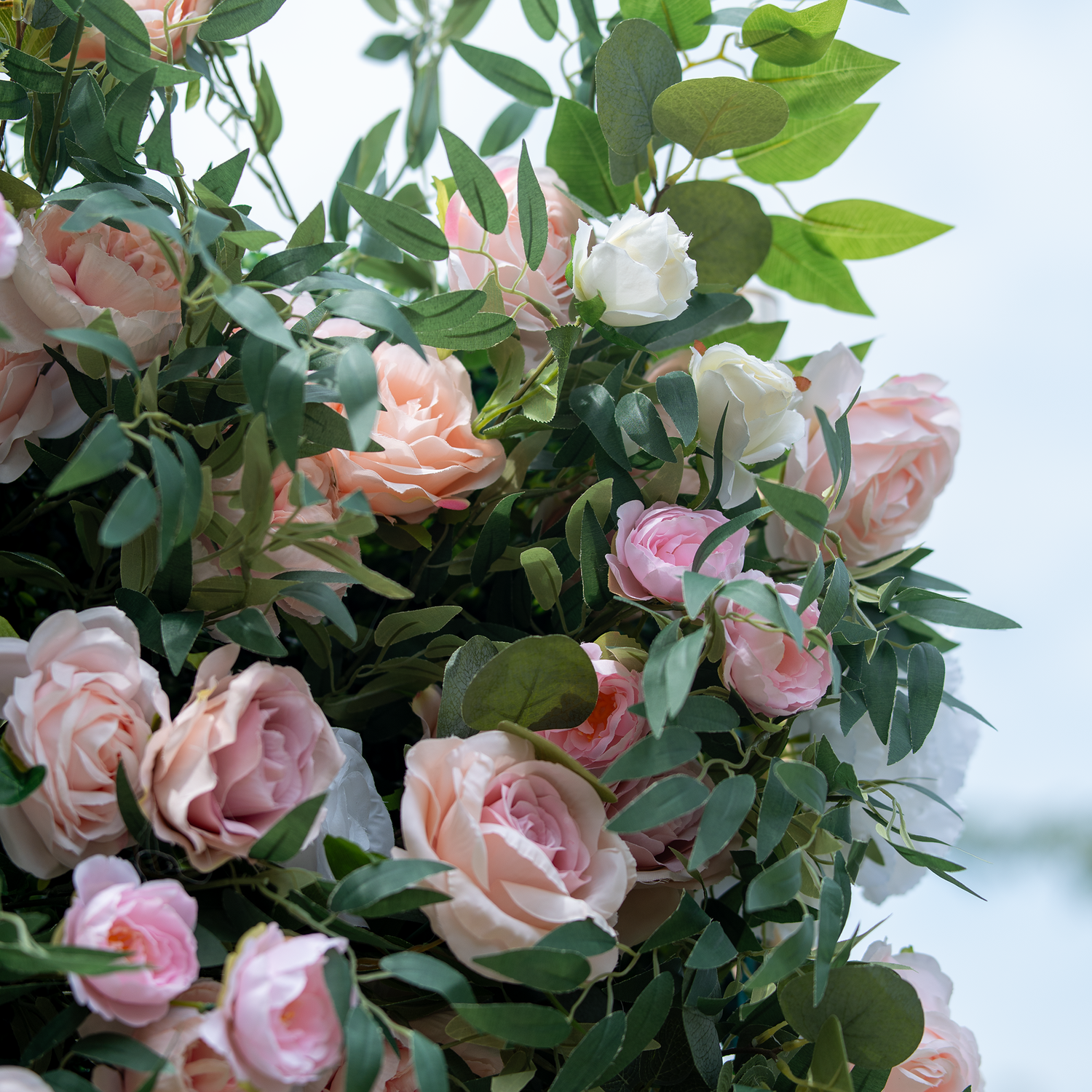 This photo displays a lush arrangement of pink and white roses, interspersed with green foliage. The soft, pastel hues of the roses create a gentle and romantic aesthetic. Ideal for events such as wedding receptions or Valentine&