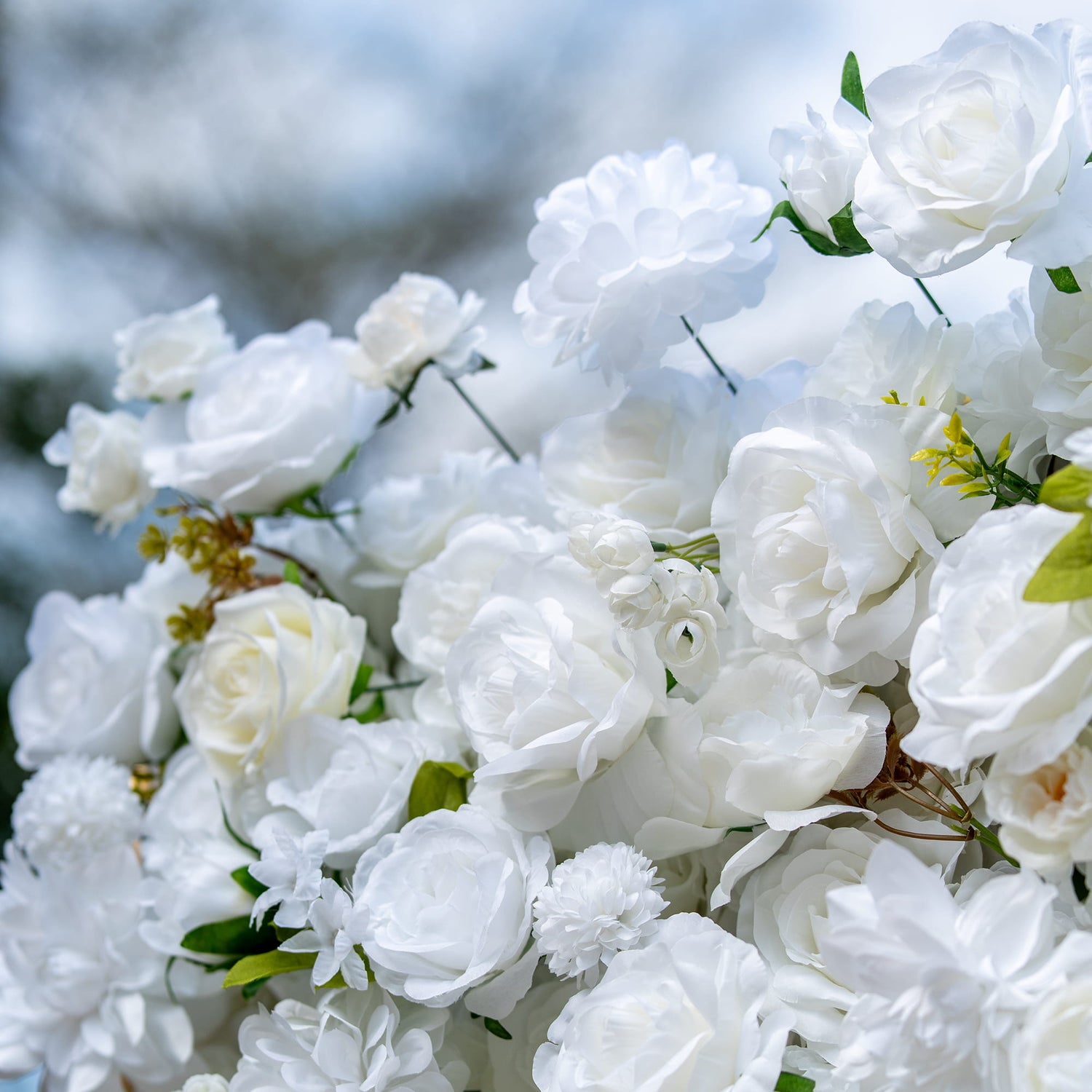 This backdrop is a lush assembly of artificial white flowers, predominantly roses, interspersed with various other blooms and green leaves. The all - white palette with green accents conveys a sense of purity and elegance.
It&