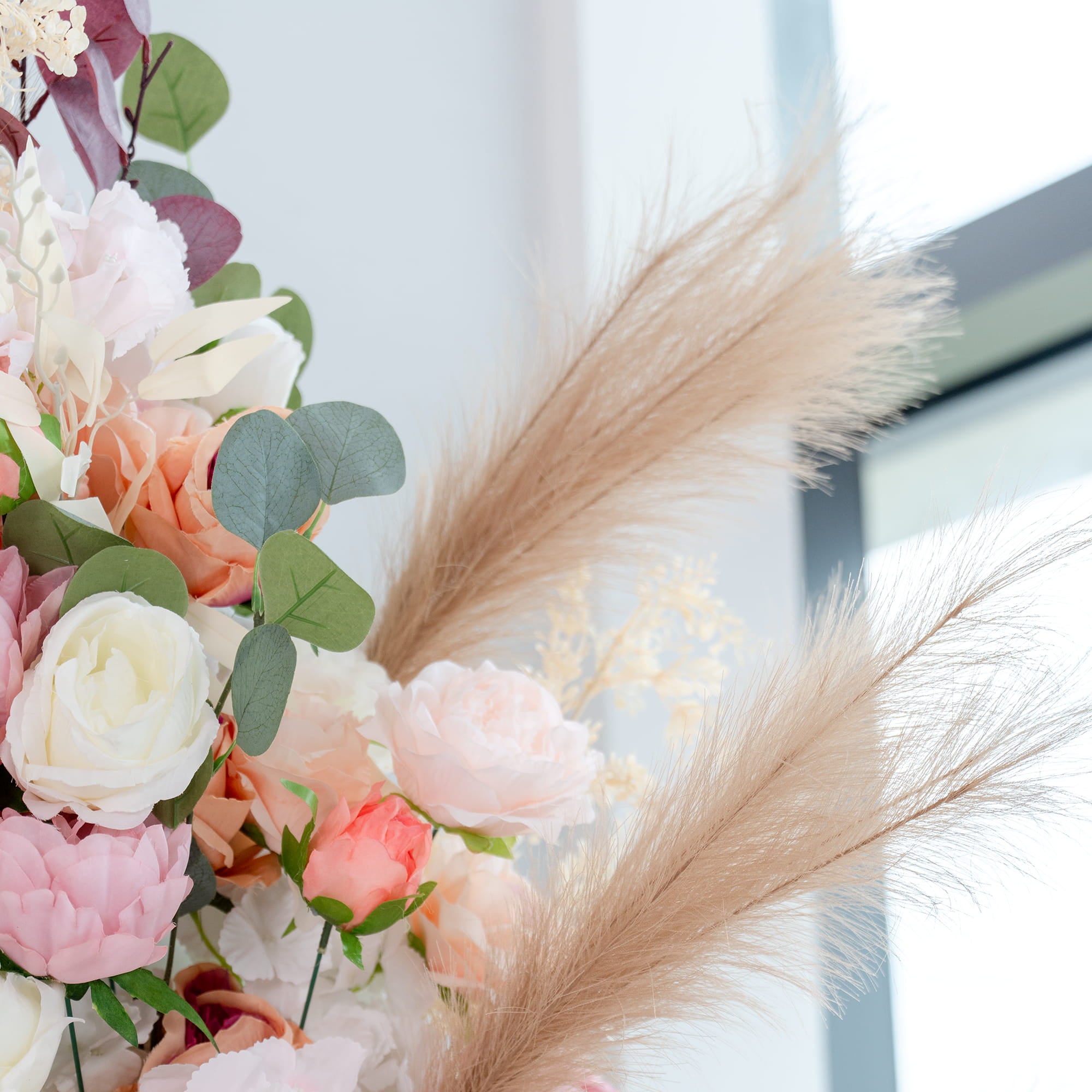 This backdrop features a lush arrangement of artificial flowers and foliage. It includes roses in shades of white, pink, and peach, along with peonies and eucalyptus leaves. Pampas - like feathers add a soft, elegant touch. The color palette is soft and pastel - toned, creating a romantic and inviting atmosphere.