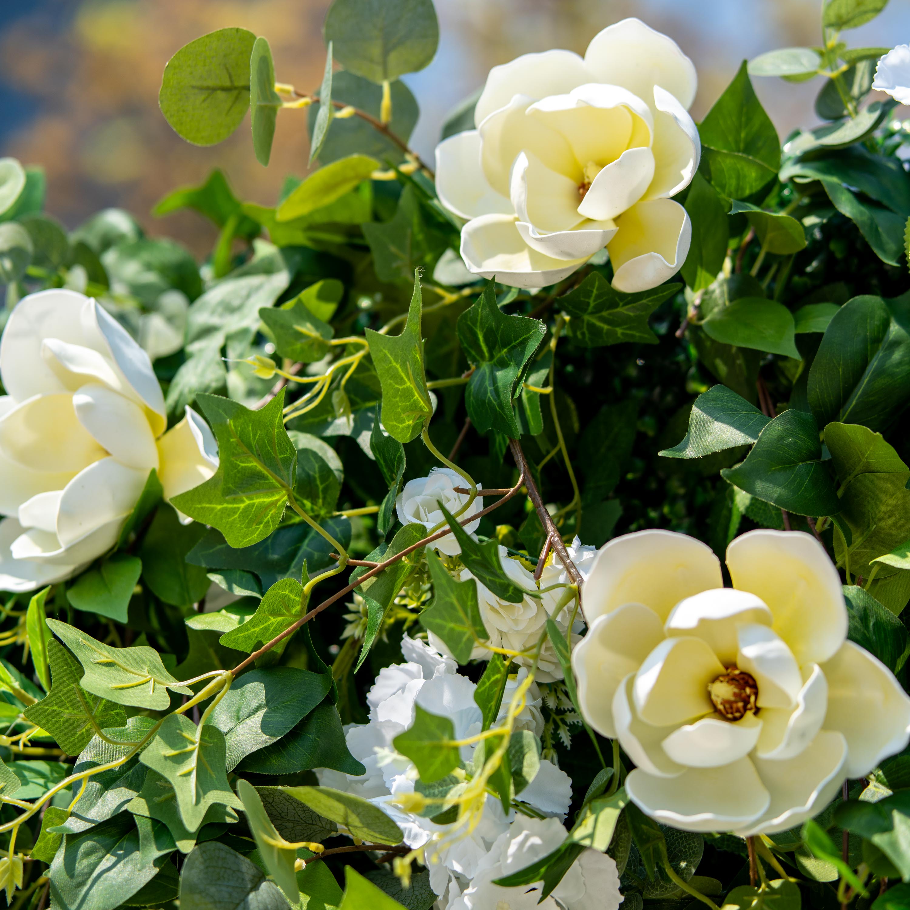 This backdrop features a rich arrangement of artificial foliage and flowers. The flowers include large, creamy - white magnolia - like blooms and smaller white roses. The greenery consists of various types of leaves, such as broad - leafed ivy and round - shaped eucalyptus - like leaves.
The color scheme is dominated by lush green foliage and pure white flowers, creating a natural and elegant style. It&