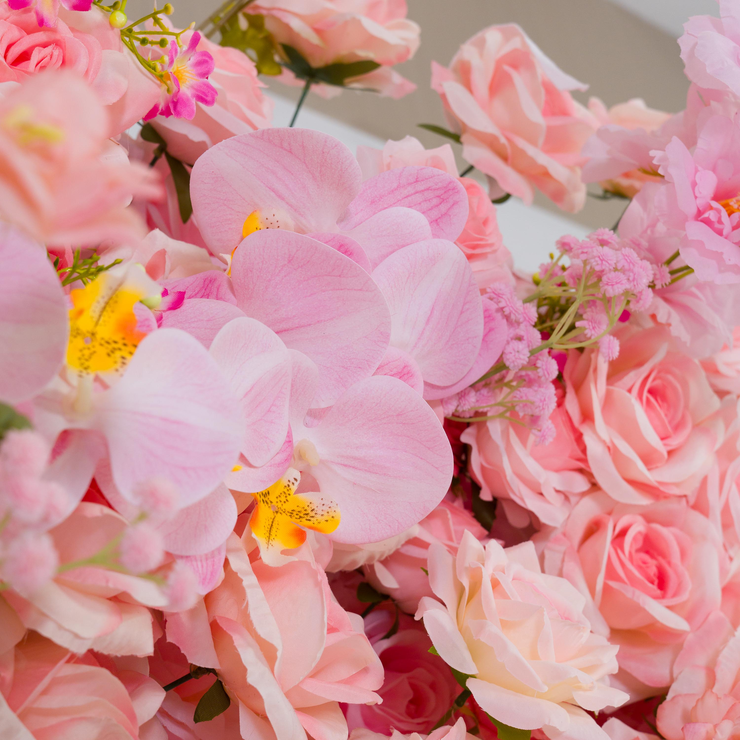 This backdrop features a lush arrangement of artificial flowers. Prominent are soft - pink roses with their classic, ruffled petals, and delicate pink orchids with yellow - spotted centers. There are also small clusters of pink filler flowers adding texture.
The colors span various shades of pink, from pale to vibrant. The overall style is romantic and elegant, making it ideal for events like weddings, bridal showers, or other celebratory functions.