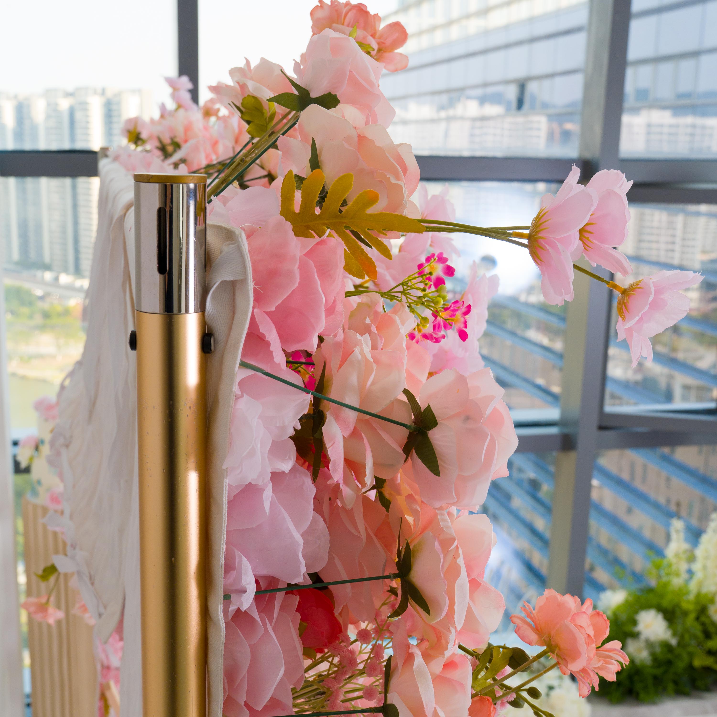 This backdrop features a vibrant arrangement of artificial flowers. There are various shades of pink, from soft pastel to brighter hues. Prominent flowers include large - petaled blooms resembling peonies, delicate pink blossoms, and small clusters of vivid pink flowers.
The style is romantic and lively, with the golden - colored metal pole adding a touch of elegance. It&