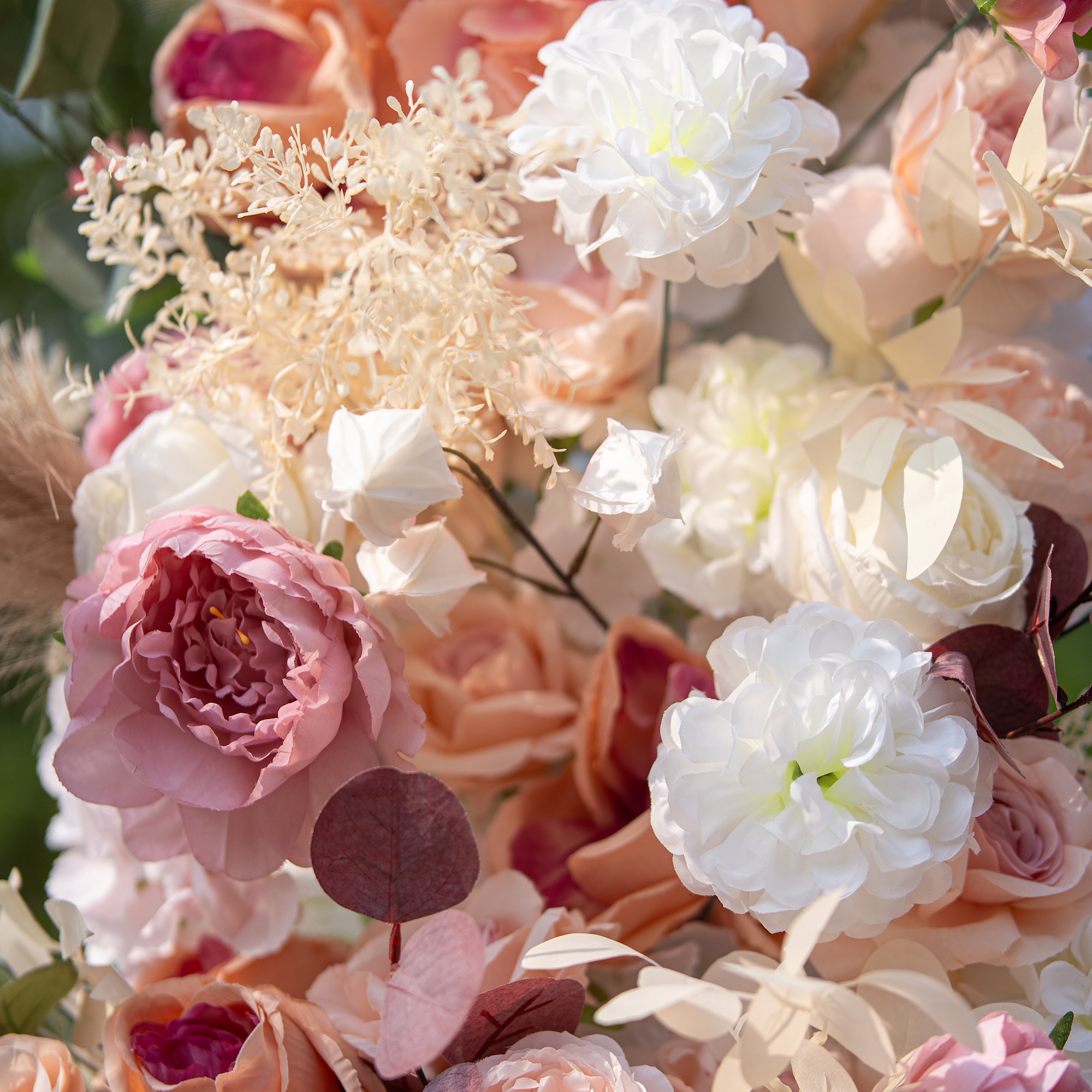 This close - up photo showcases a lush floral arrangement with roses and peonies in soft pink, peach, and white hues. Accented by dried elements and eucalyptus leaves, it has a blurred green backdrop. The style is romantic and elegant, ideal for weddings or high - end garden events.