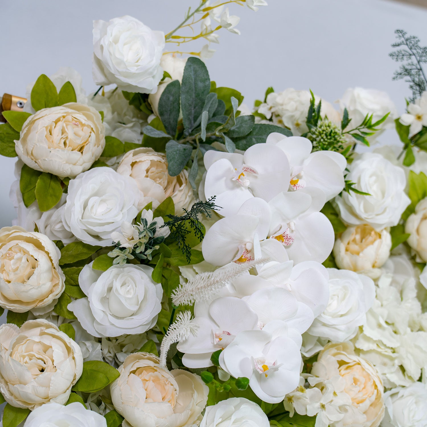 This backdrop features a blend of white roses, peonies, and orchids with green foliage, following a soft white and cream color theme. It exudes elegance, making it perfect for weddings, bridal showers, or upscale galas.