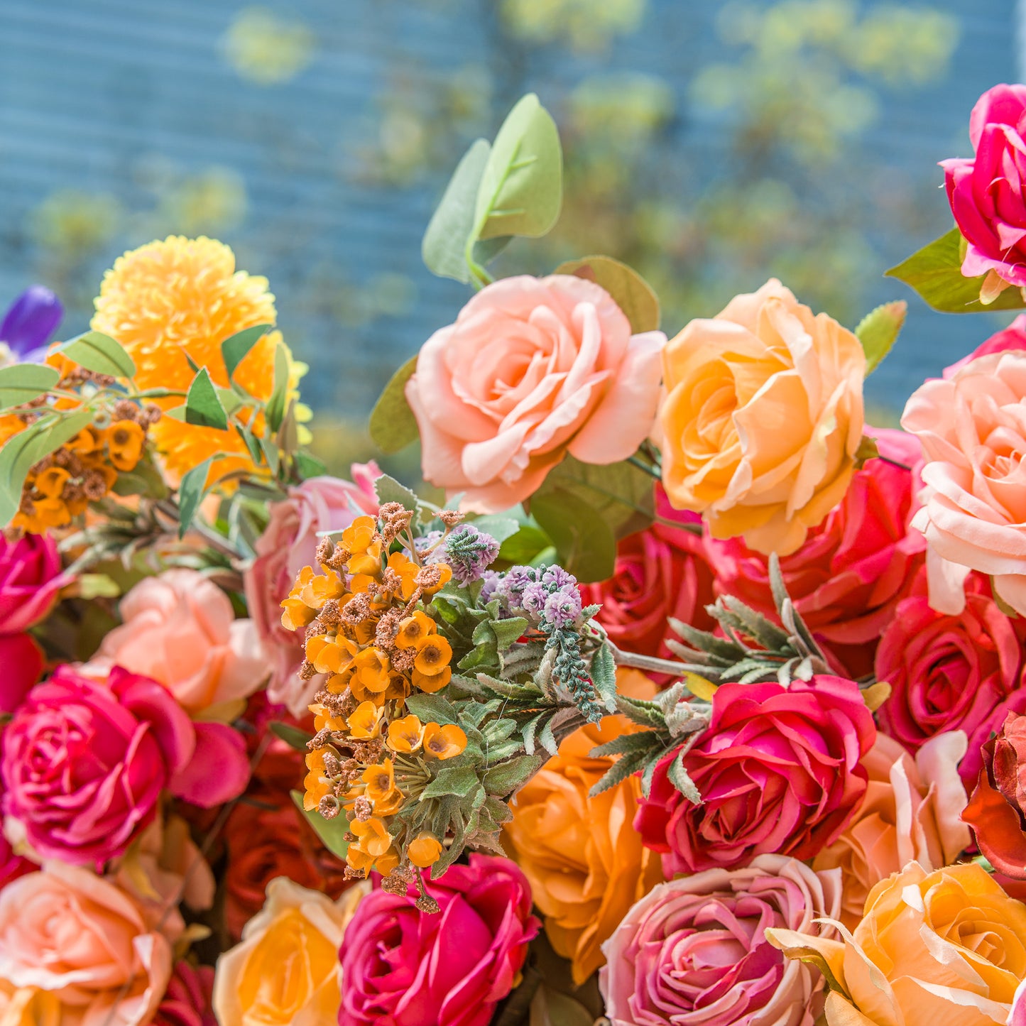 A vibrant floral arrangement showcases a mix of blooms. Soft peach and bright yellow roses take center stage, surrounded by deep pink blossoms. Accents of orange flowers, delicate purple sprigs, and green foliage add texture. The varied colors and textures create a lively, eye - catching display, perfect for adding a burst of natural beauty to any setting.