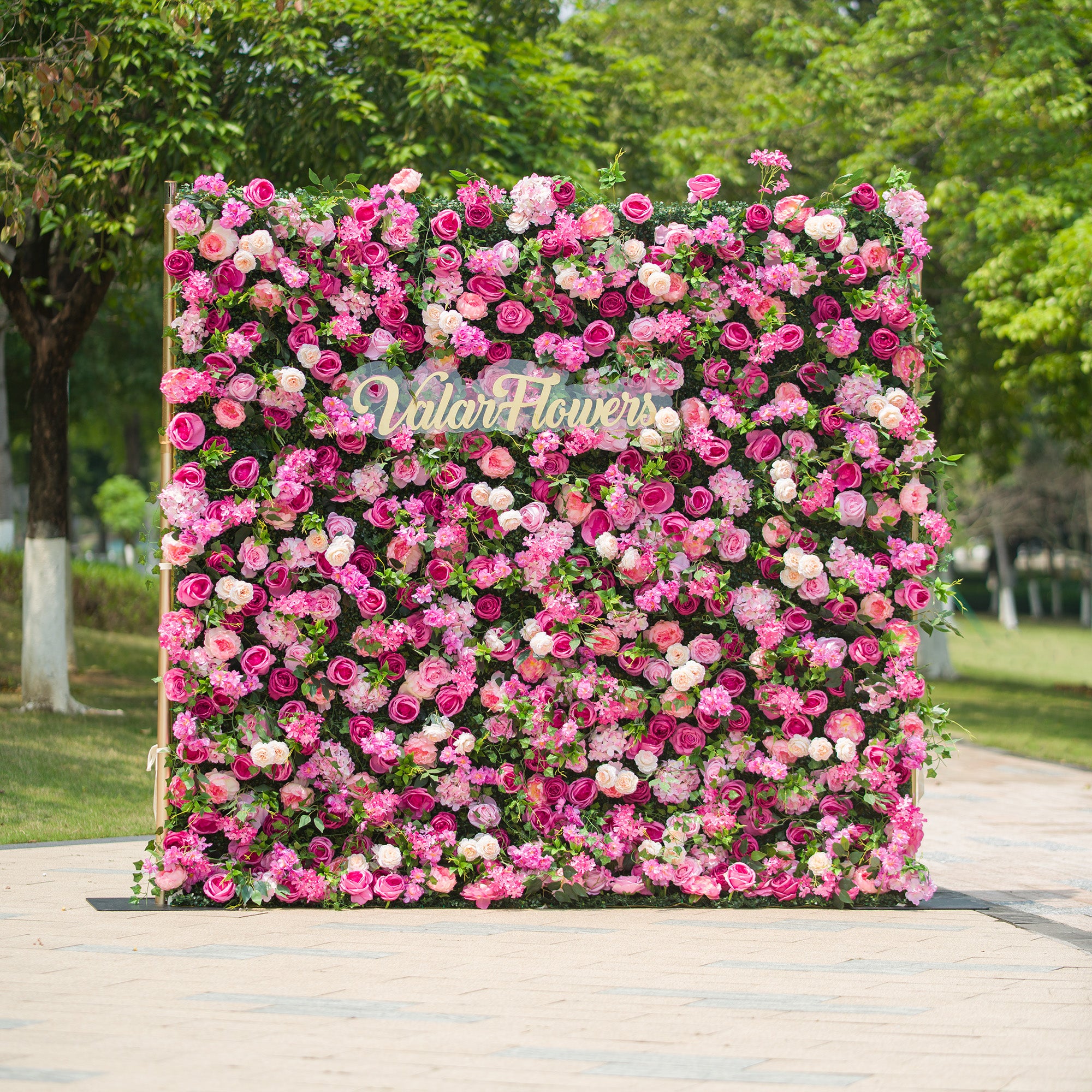 This photo showcases a large, vibrant floral backdrop filled with an array of pink and white roses, along with other assorted flowers, all interspersed with lush green foliage. The text "ValarFlowers" is prominently displayed in elegant golden lettering. Ideal for events like garden weddings or a "Pink Paradise Party", it creates a lively and romantic atmosphere, making it a stunning decorative centerpiece for festive and celebratory occasions.
