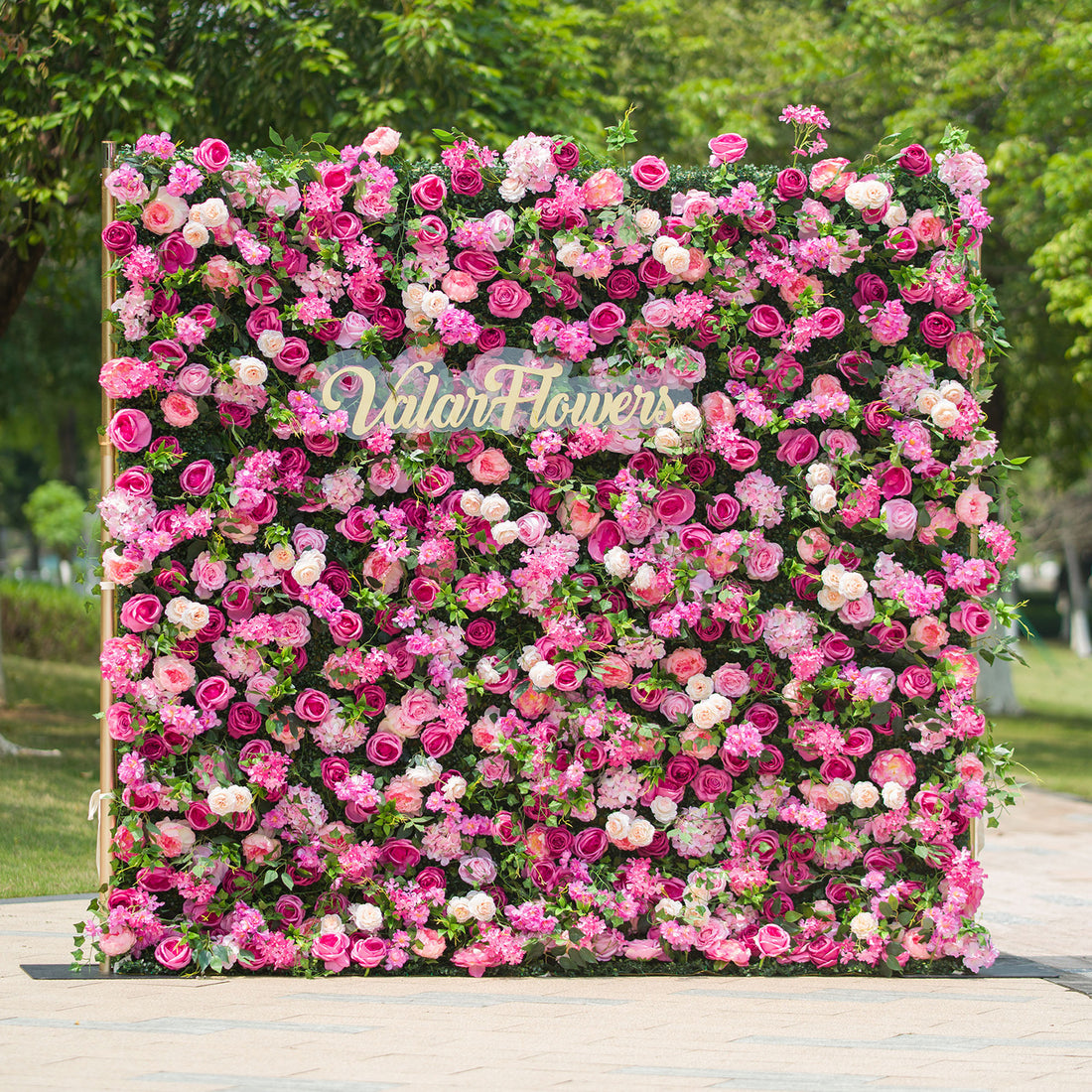 This photo showcases a large, square floral backdrop densely covered with an array of pink and white roses, along with other assorted pink flowers, all set against lush green foliage. The text “ValarFlowers” in elegant lettering stands out prominently. Ideal for events like a “Pink Paradise” garden party or a vibrant wedding, it exudes a lively and romantic charm, perfect for outdoor celebrations.