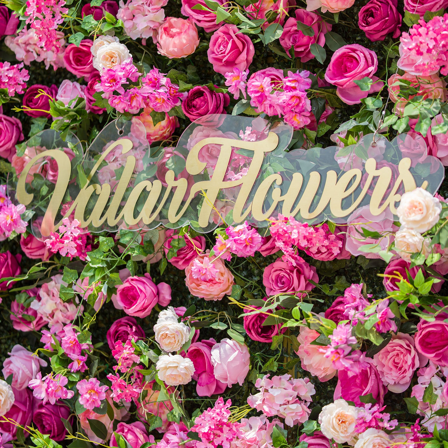 This photo showcases a dense floral backdrop brimming with an array of pink and white roses, along with other assorted pink flowers, all nestled among lush green foliage. The text “ValarFlowers” in elegant golden lettering stands out prominently. The vibrant blooms create a lively, romantic atmosphere, ideal for events like garden weddings or spring - themed parties.